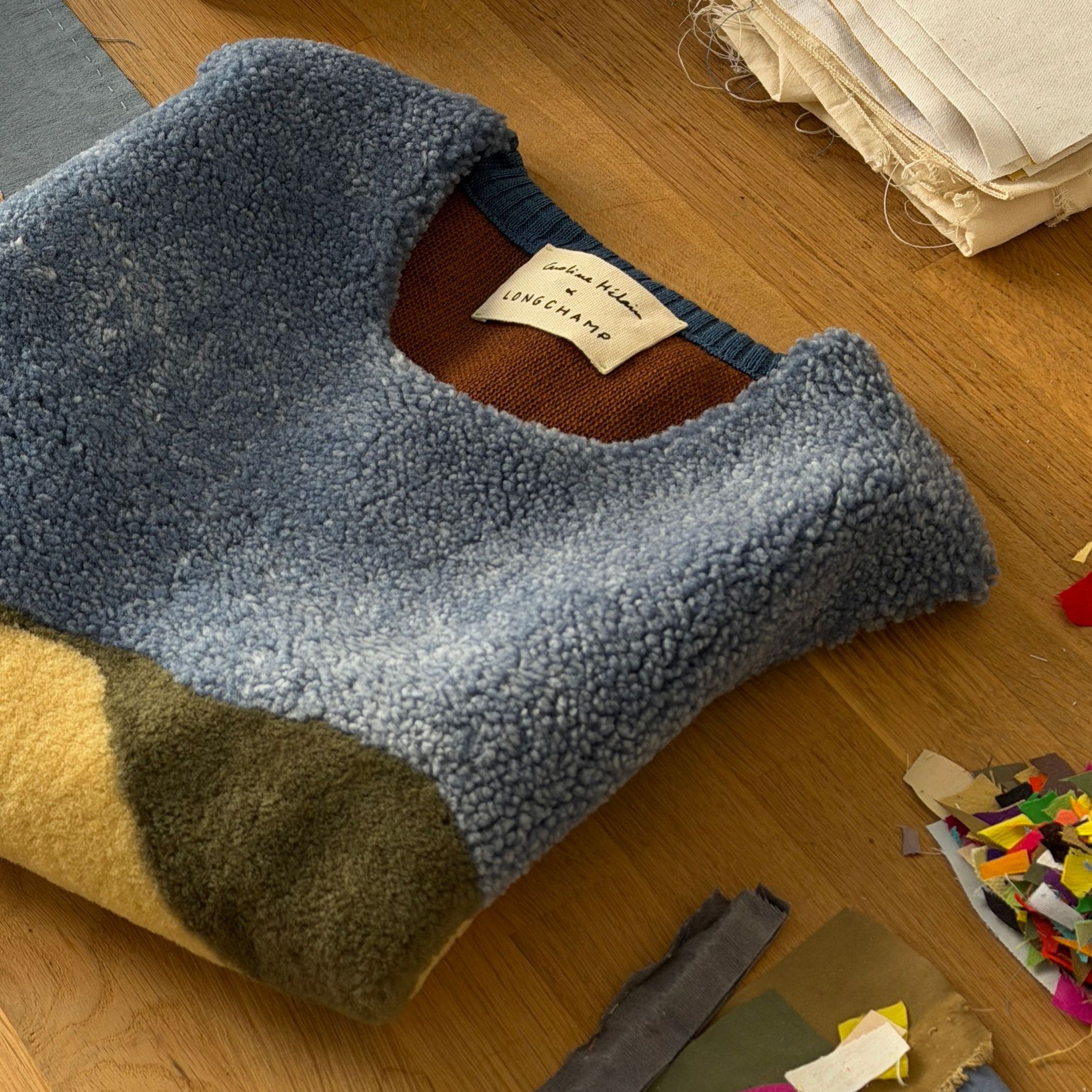 The sleeveless calf leather and bouclé wool top from the Caroline Hélain x Longchamp collection, laid out in Hélain's Brussels studio beside spools of embroidery thread and offcuts from her fabric archive.