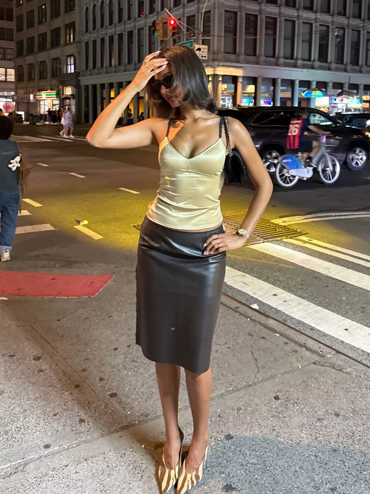 Jamilla Strand wears a yellow satin top, black leather midi skirt and patterned heels