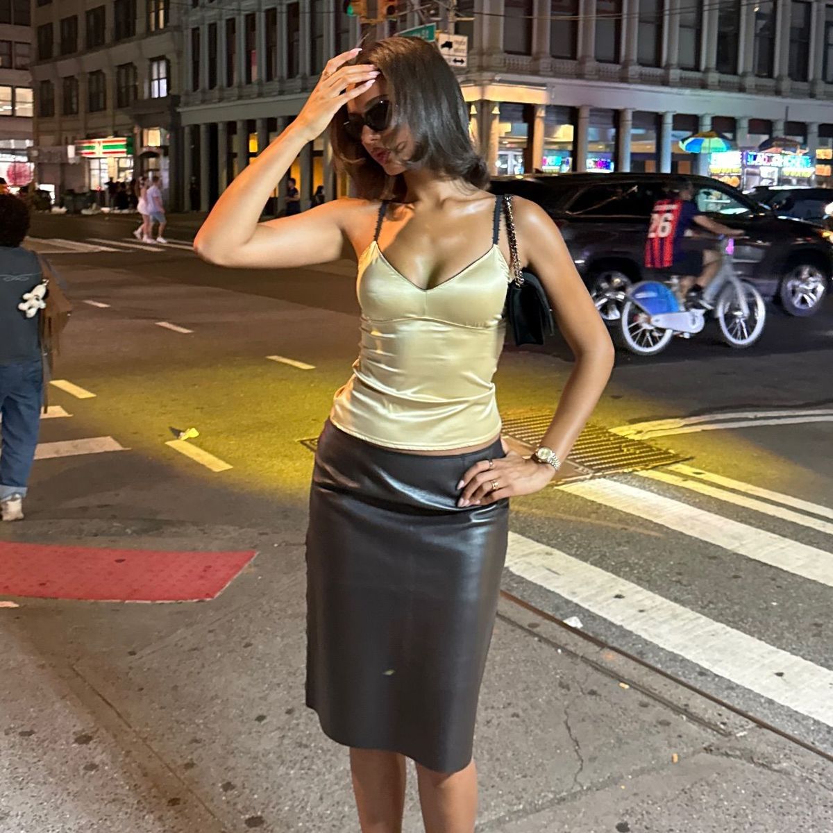 Jamilla Strand wears a yellow satin top, black leather midi skirt and patterned heels