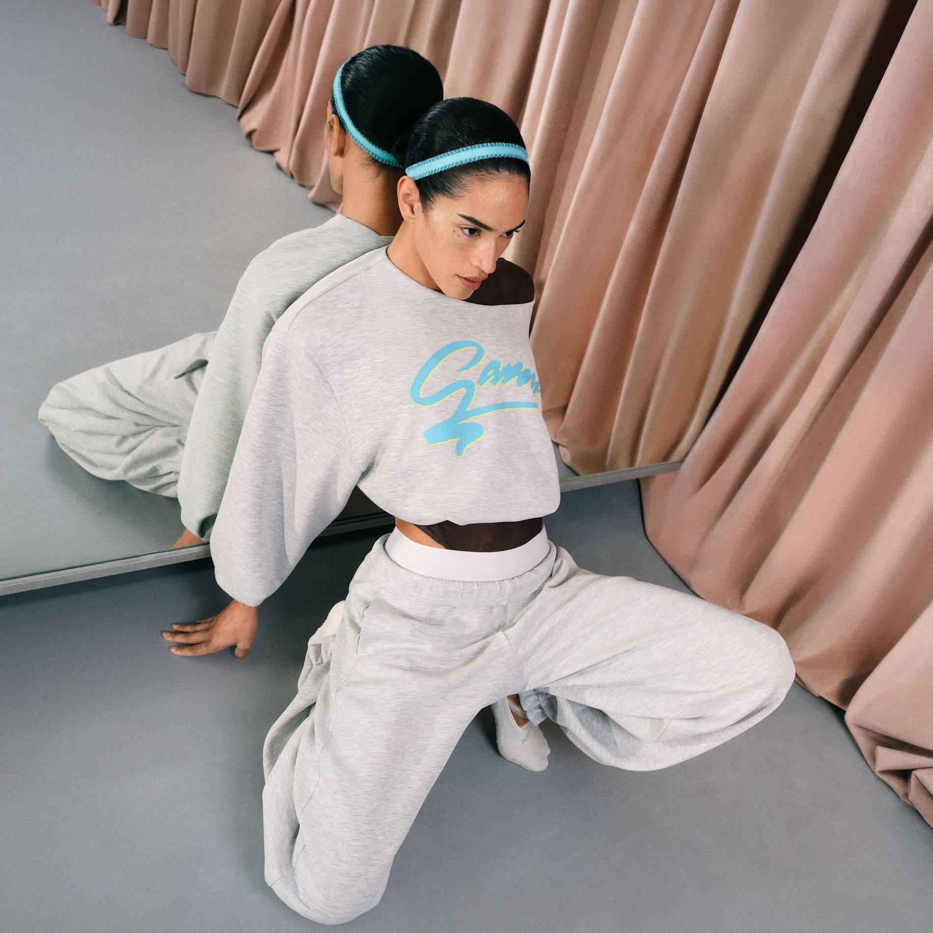 Model poses in the new grey sweat set from the Ganni x Lululemon collaboration