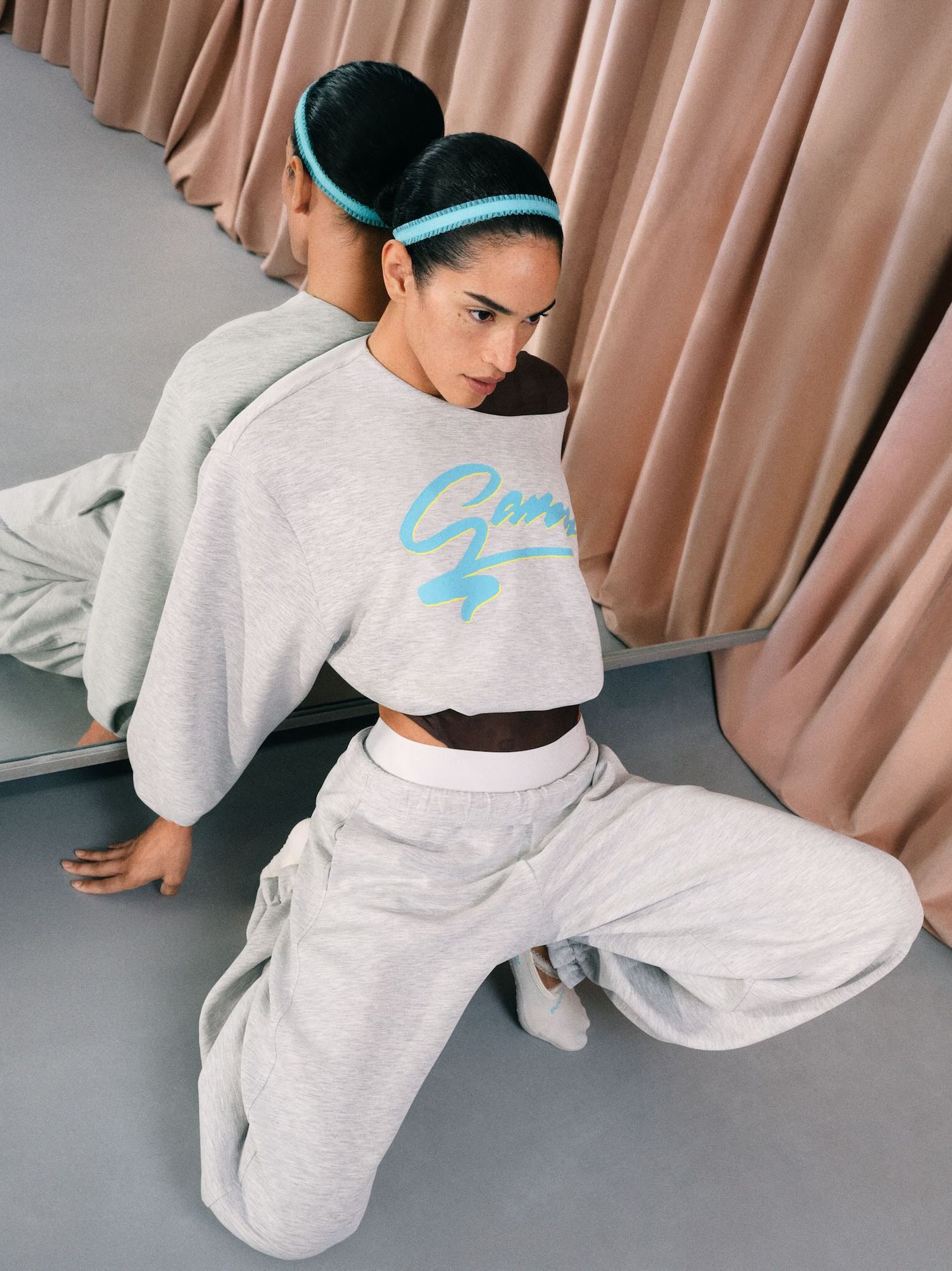 Model poses in the new grey sweat set from the Ganni x Lululemon collaboration