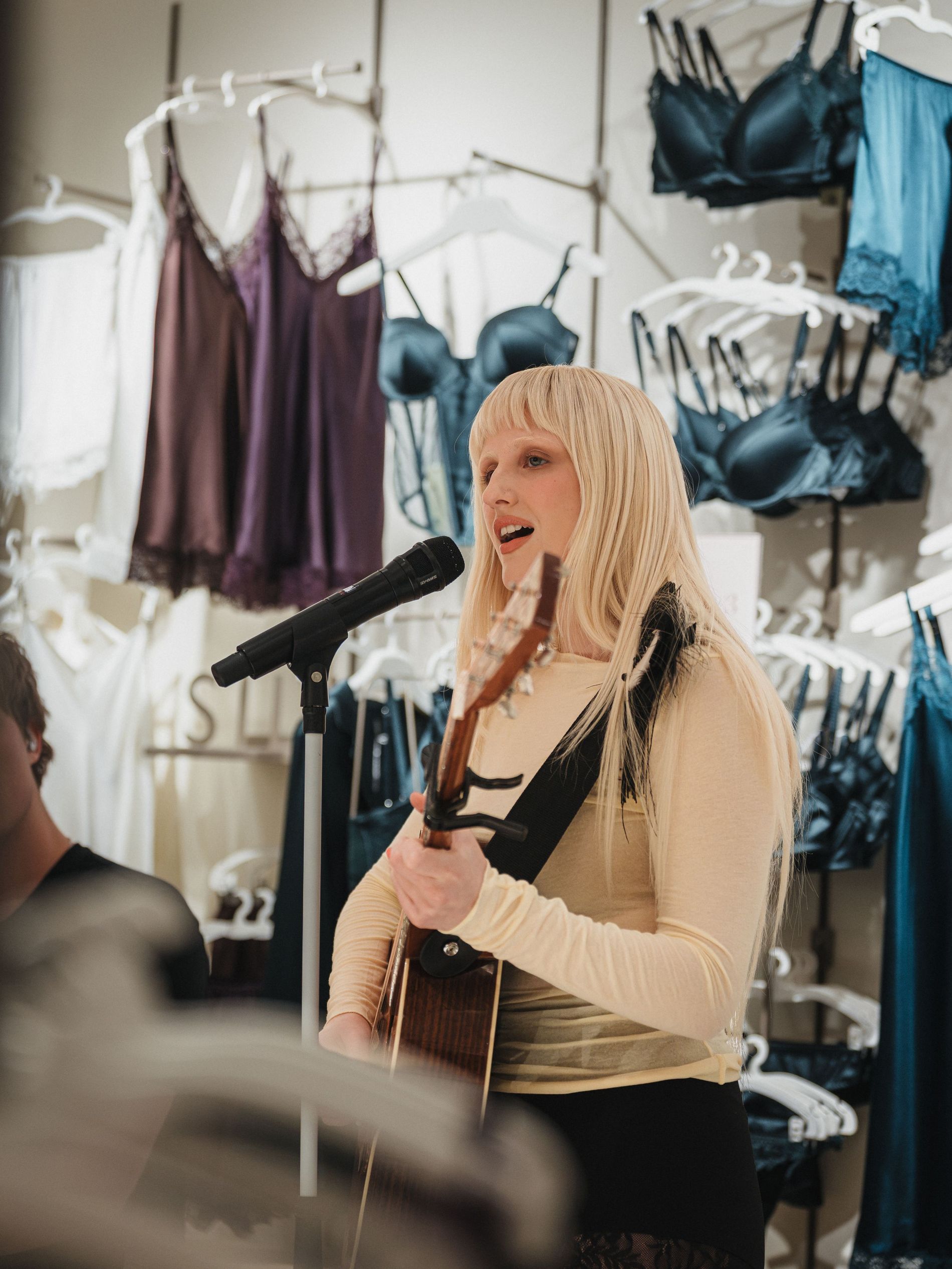Fanny Avonne singing at the Intimissimi X Vogue Scandinavia event in the background satin underwear from intimissimi is hangning in plum, brown and blue