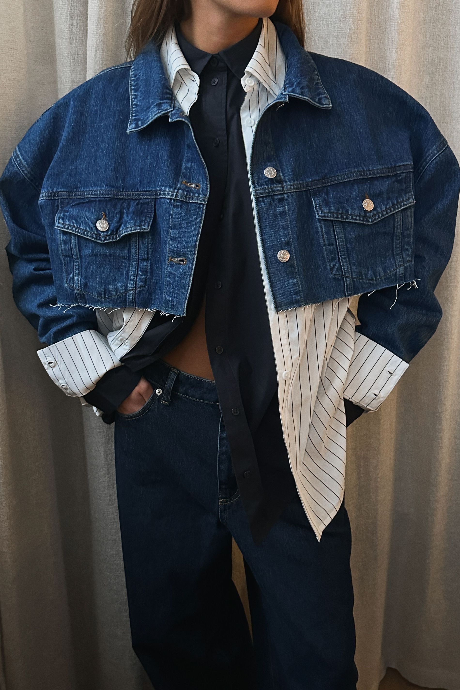 Model poses with cropped denim jacket, two shirts and a pair of jeans for NA-KD's Future Remake collection