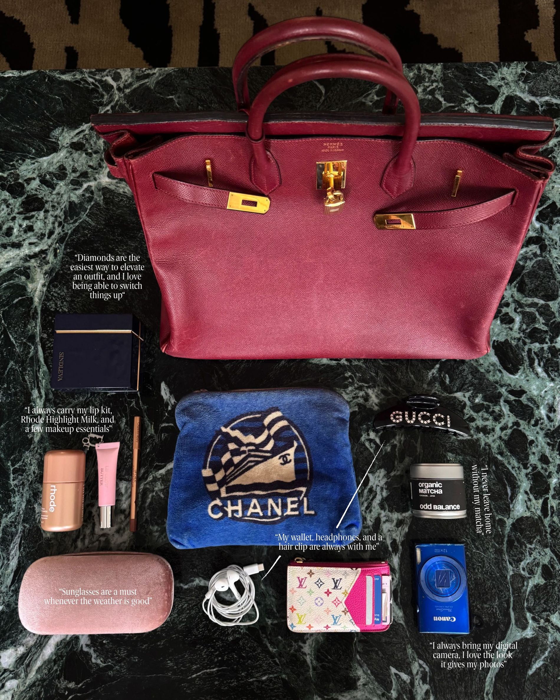 Emili Sindlev's red leather bag during CPHFW 2026, filled with dimonds, makeup, sunglasses, headphones, hair clip, wallet and digital camera.