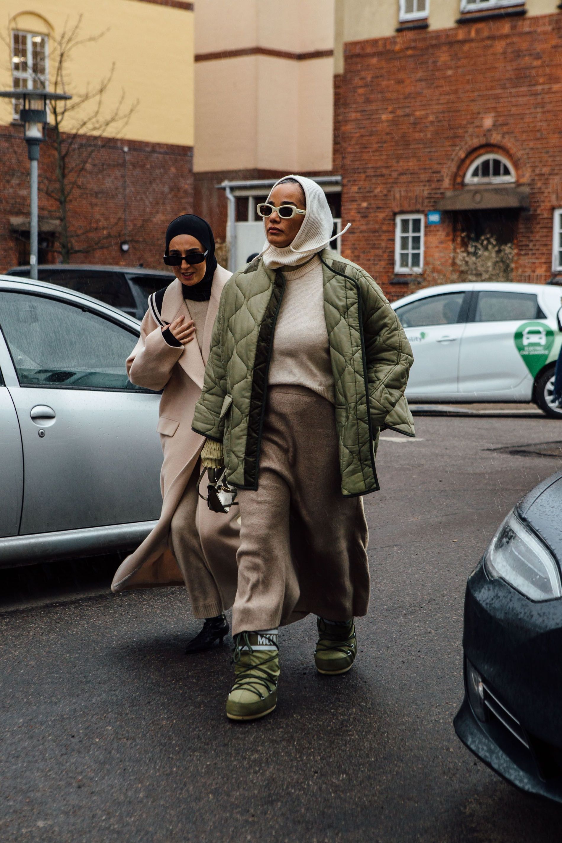 A guest wears a white knitted balaclava, a green quilted jacket and matching moon boots