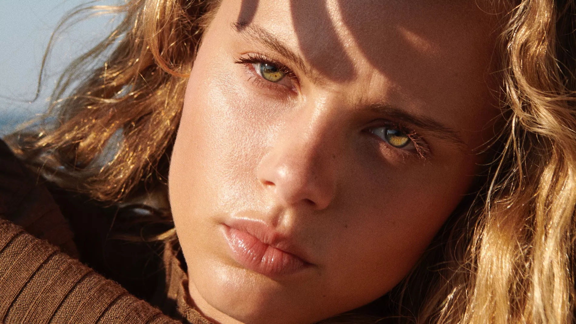 Close-up of model posing in the sun, wearing a warm knit, with a perfect tan