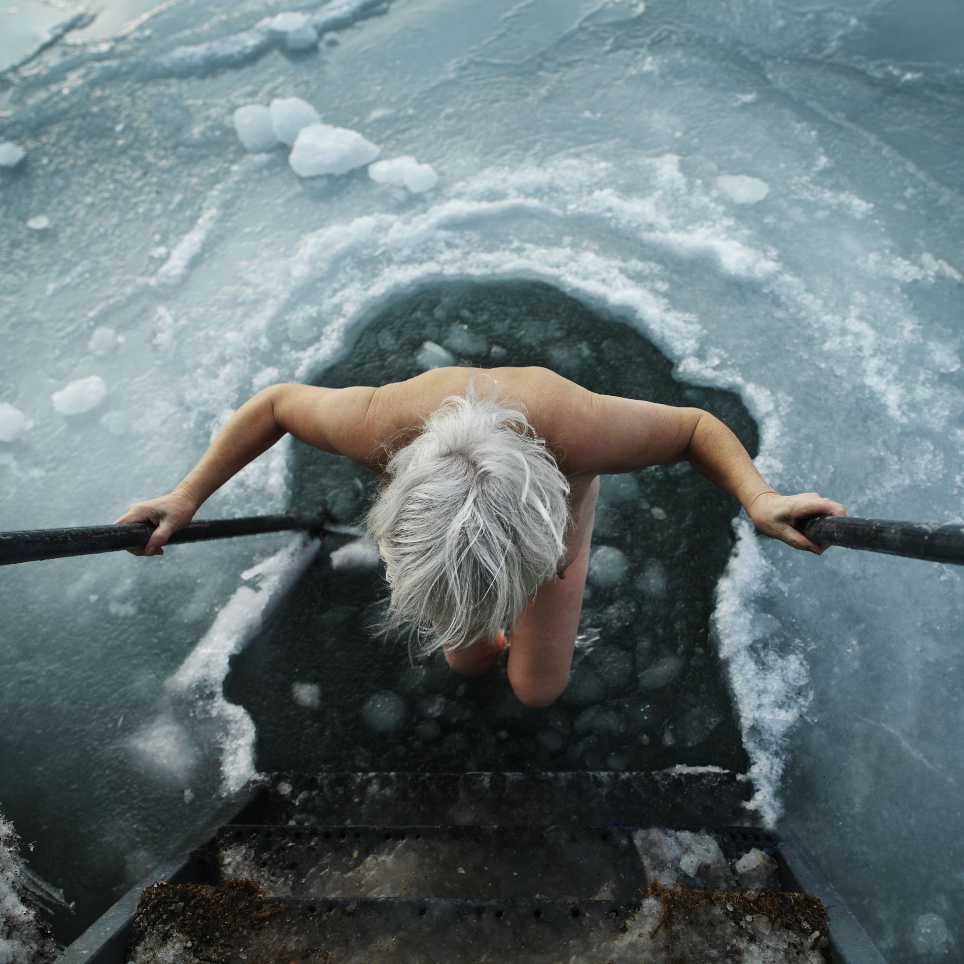 Woman hoisting herself out of icy water
