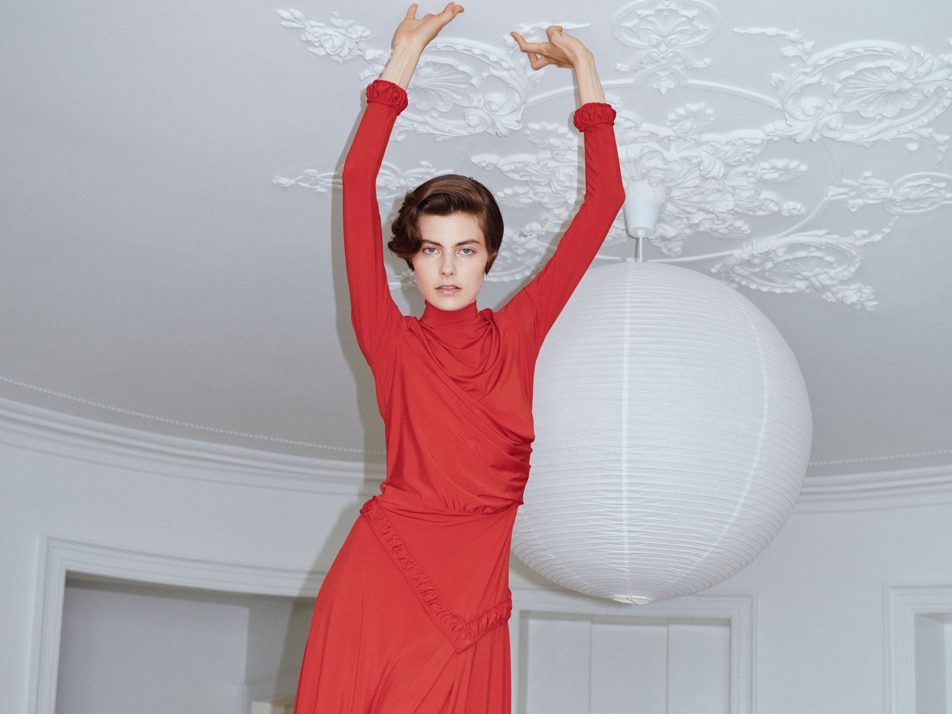 Image from Forza Collective SS27, model in a red dress standing on a table.