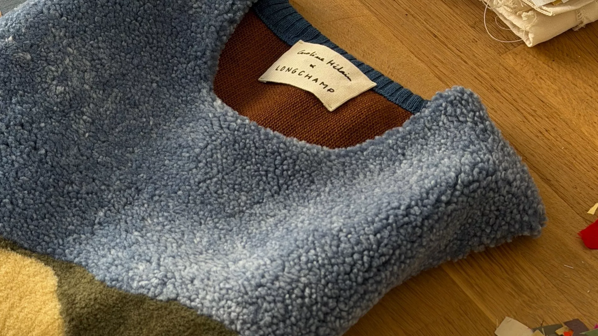 The sleeveless calf leather and bouclé wool top from the Caroline Hélain x Longchamp collection, laid out in Hélain's Brussels studio beside spools of embroidery thread and offcuts from her fabric archive.