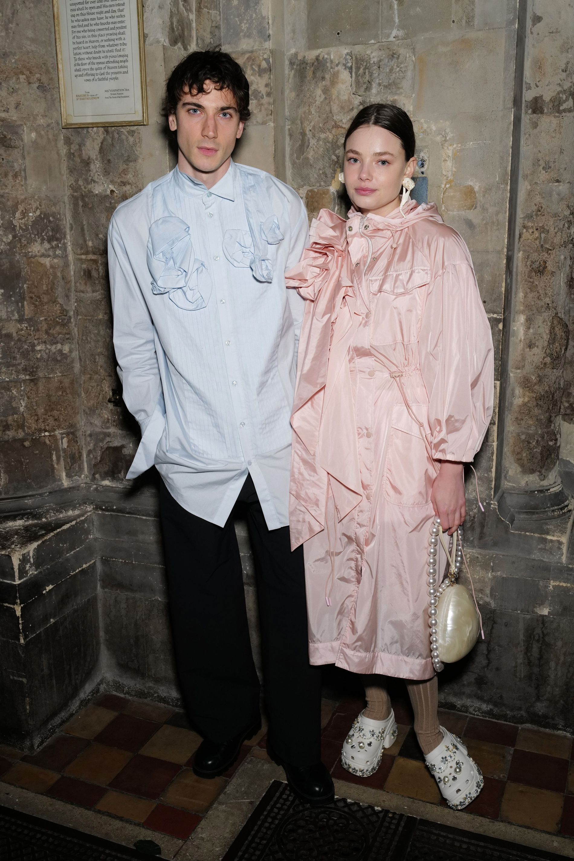 Kristine Frøseth wearing a pink bow-adorned coat and embellished crocs posing with Buccaneers co-star Guy Remmers