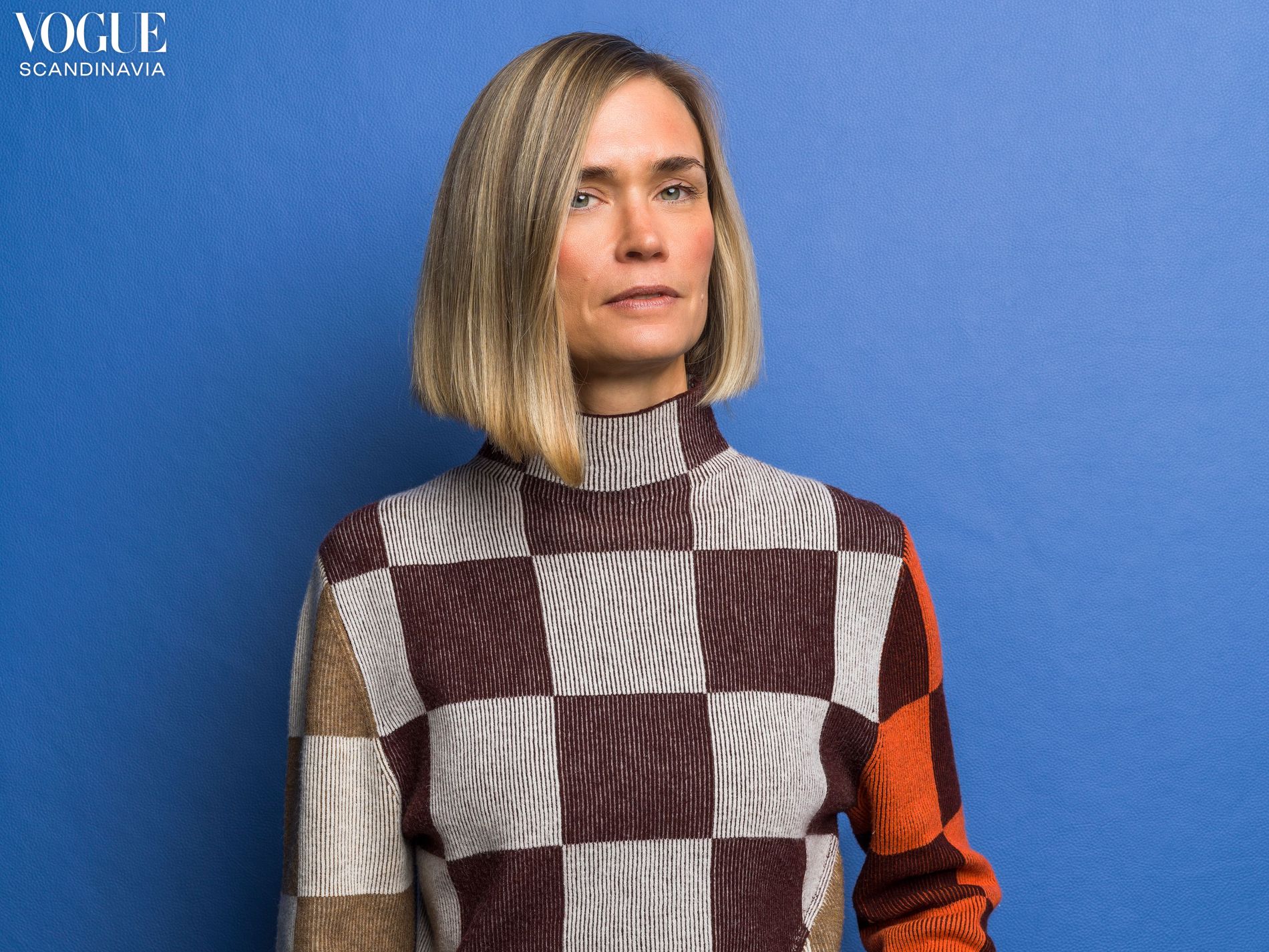 The person in the image is the Swedish designer and colorist Tekla Evelina Severin wearing a Stine Goya Long Sleeve Asymmetric Top in chocolate combo on a bright blue background