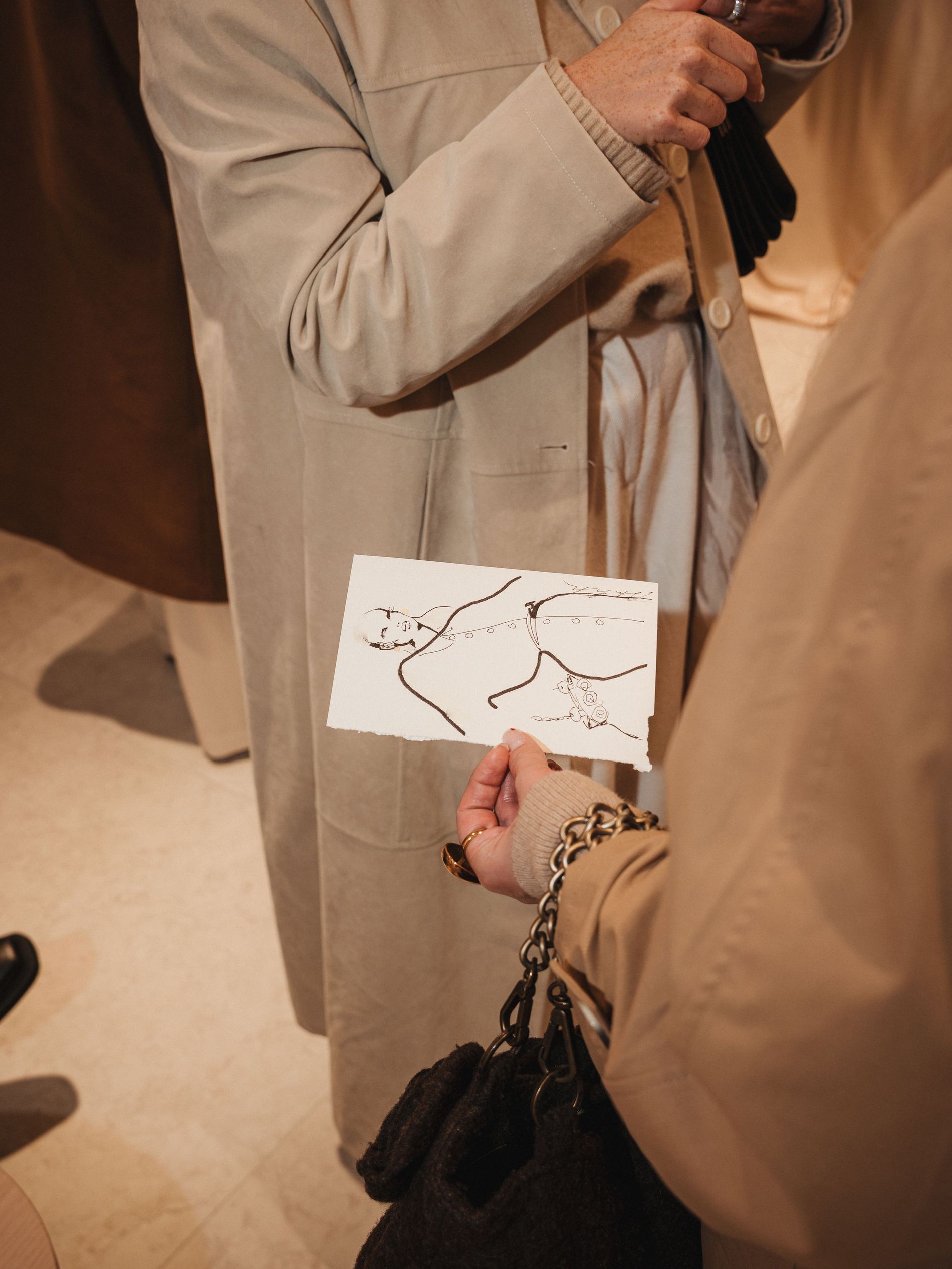 Girls in beige trenchcoats holding a caricature