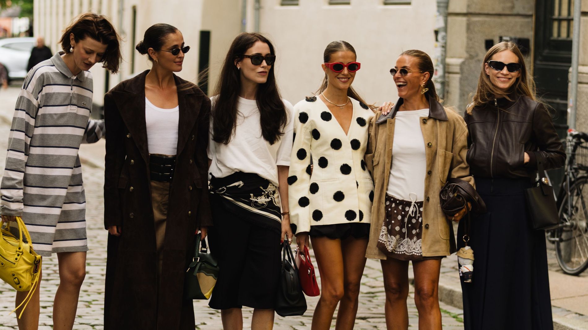 six girls standing on the street smiling during Copenhagen Fashion Week wearing different colorful and standout outfits 