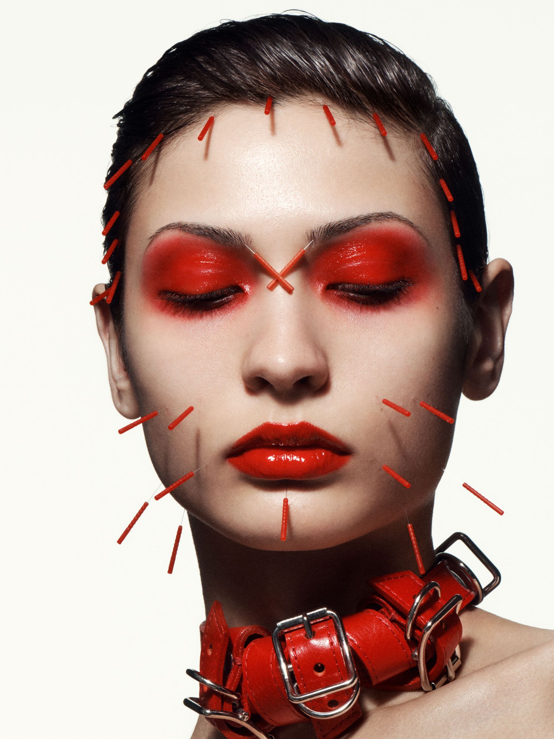 Model wearing red makeup and red acupuncture needles