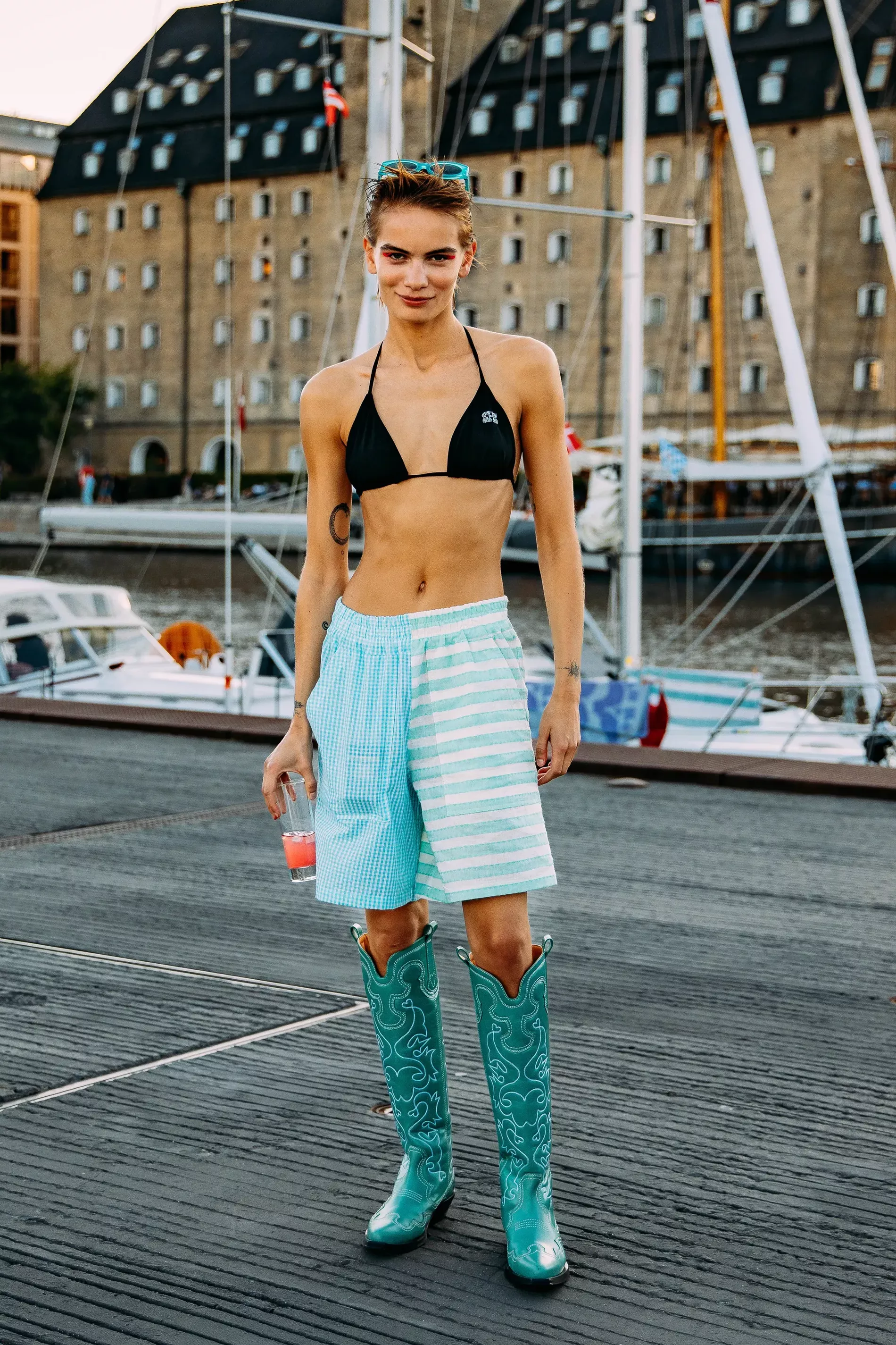 Copenhagen fashion week guest matches turquoise striped shorts with bikini top and cowboy boots 