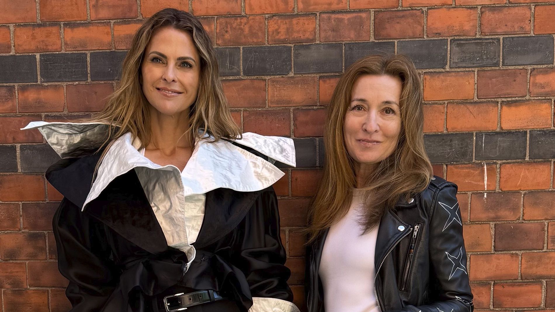 Princess Madeleine and Martina Bonnier stand side by side by a brick wall