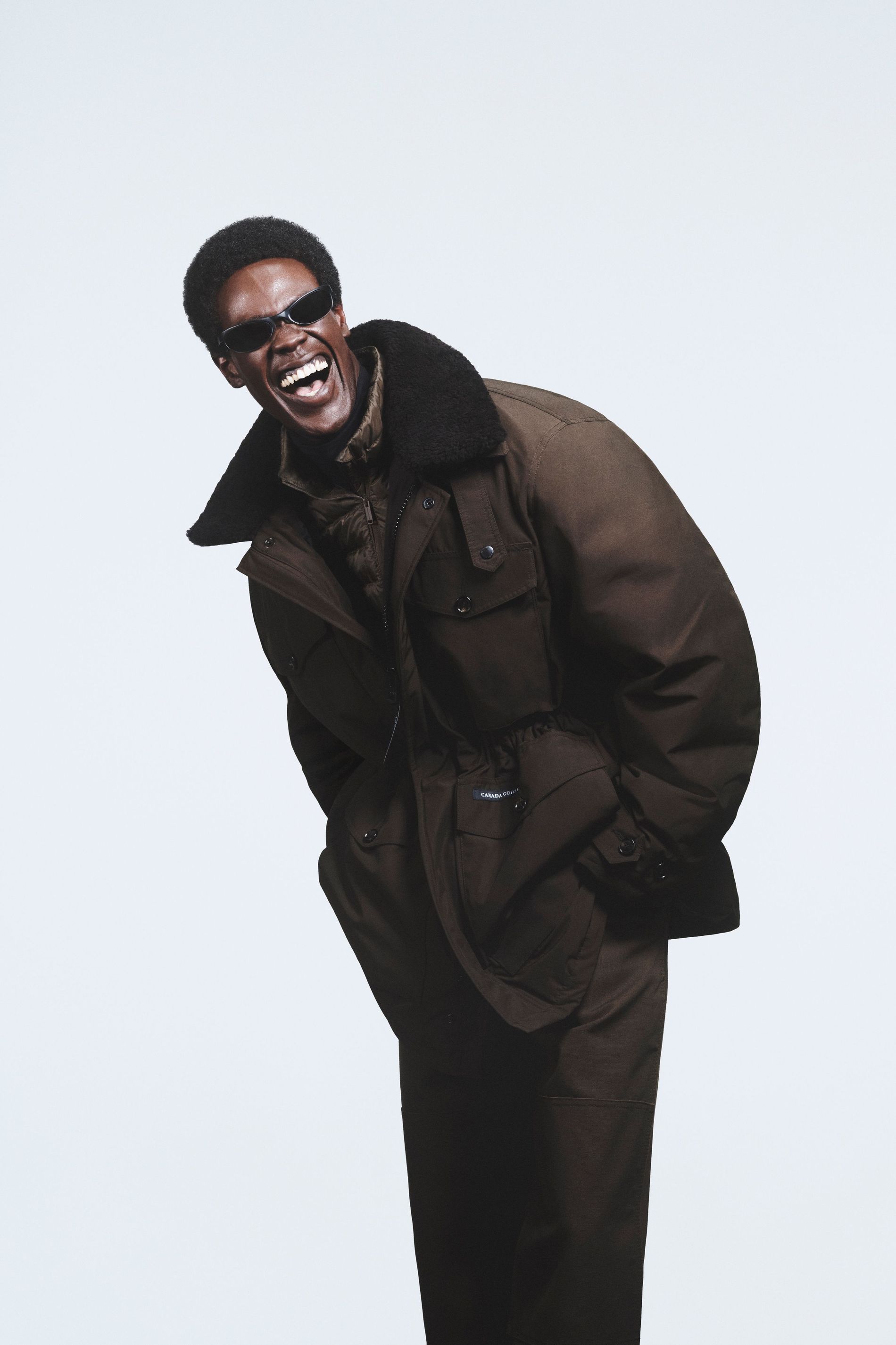 Smiling model wears an all-brown outerwear set from Canada Goose