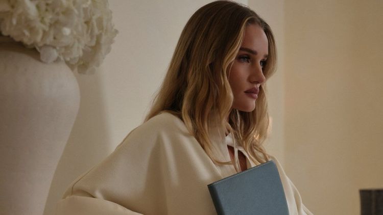 Rosie Huntington-Whiteley wears cream dress in monochromatic room holding pale blue notebook