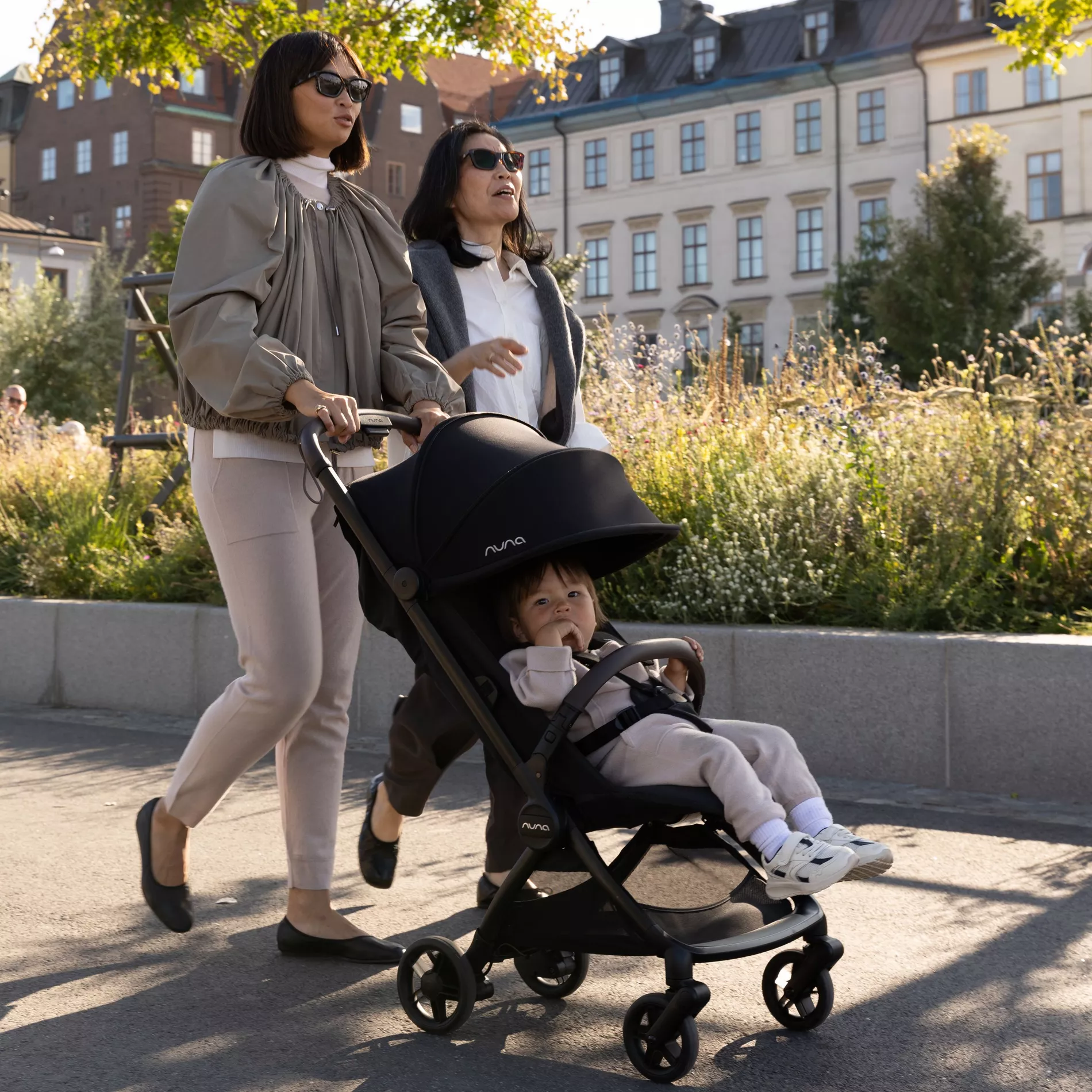 A grandmother and mother push. child in the Nuna VIAA cabn around city streets