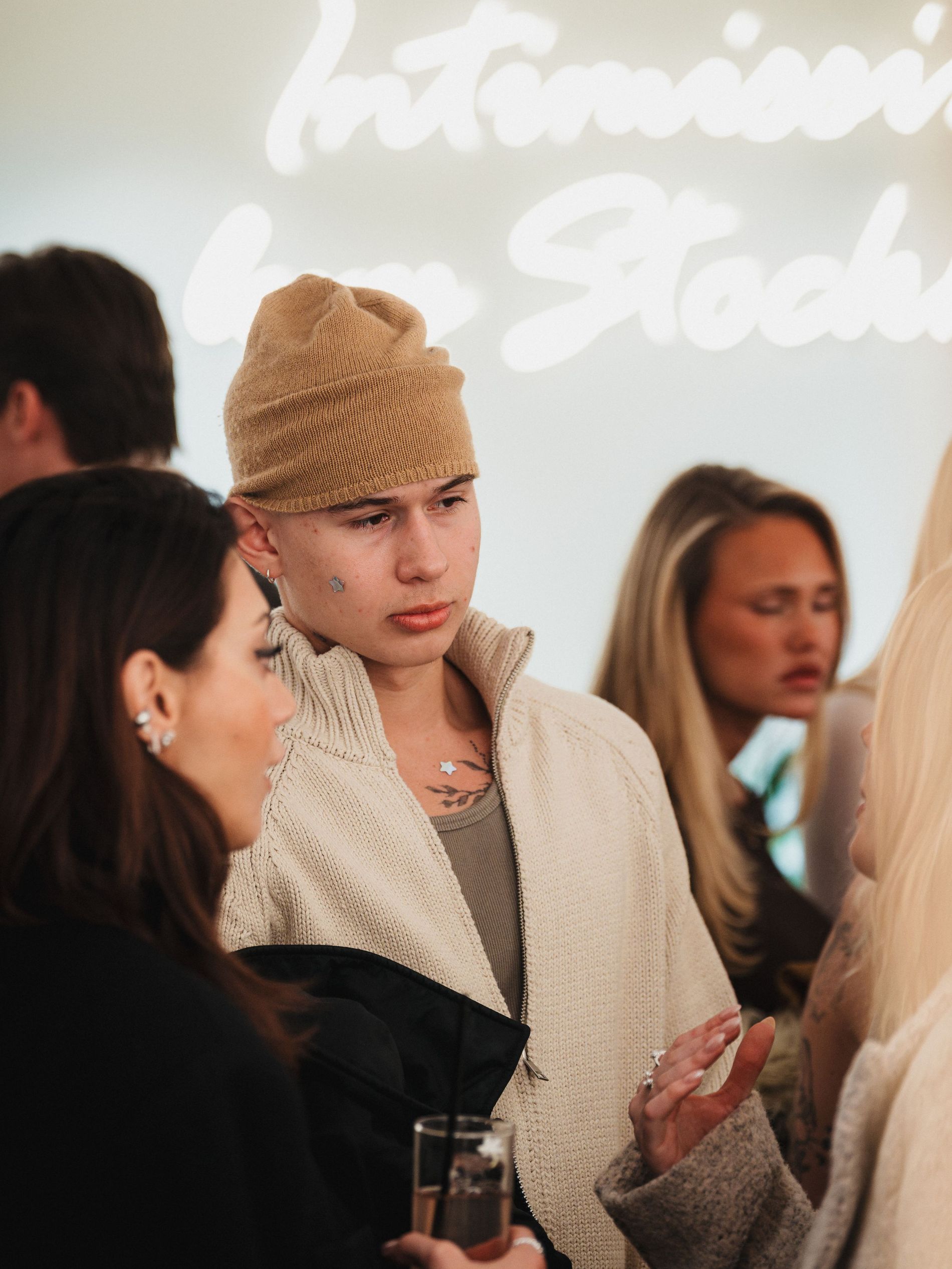 Melvin Carrere at the Intimissimi X Vogue Scandinavia event wearing a beige knitted cardigan and a camel brown kashmir  knitted cap
