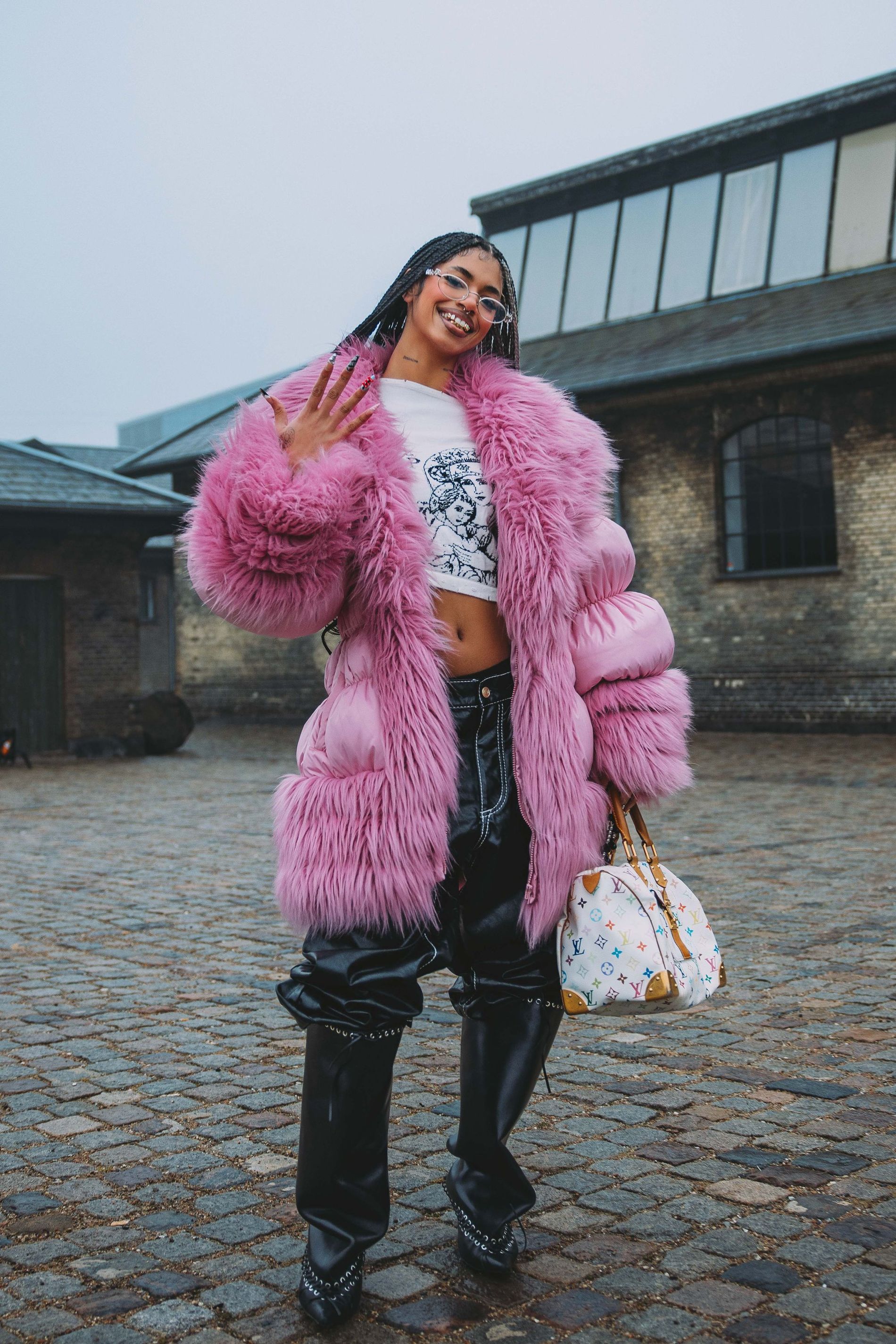 A guest at Copenhagen Fashion Week poses for a street style photo wearing a fuzzy pink coat 