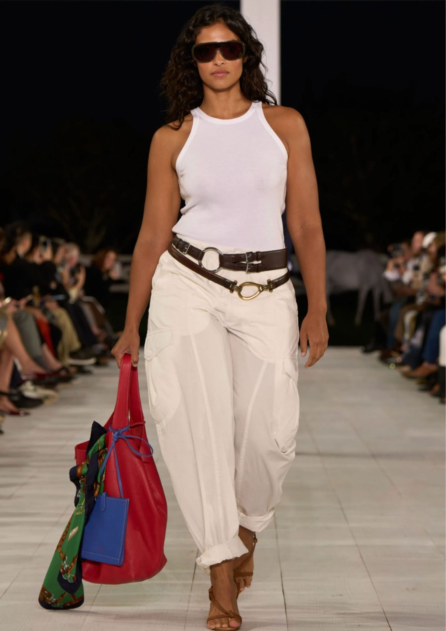 Model walking the SS25 Ralph Lauren runway, wearing white cargo pants and white tank top and stacked belts 