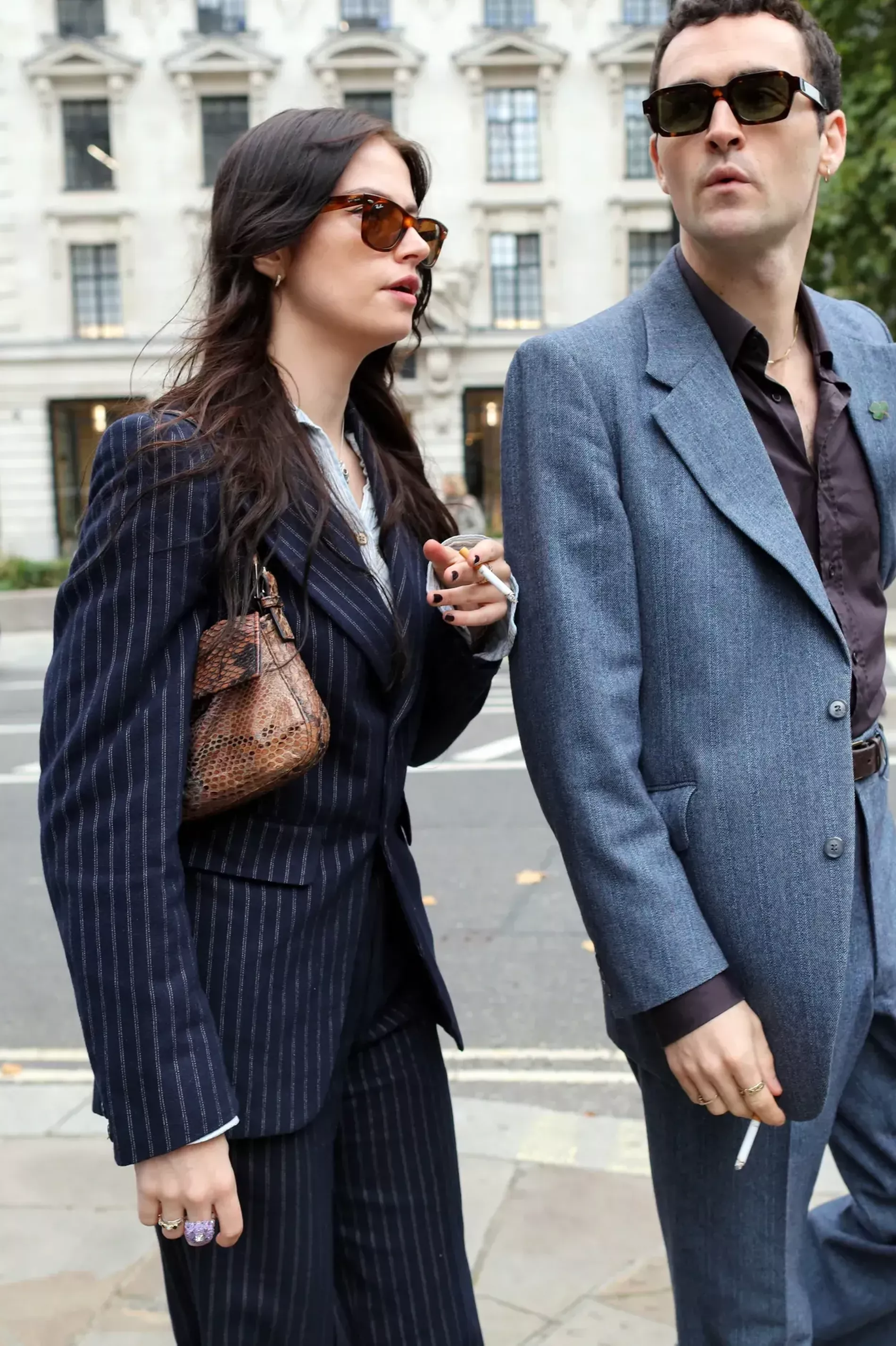 London Fashion Week guest pairs pinstripe suit with brown leather bag and matching sunglasses 