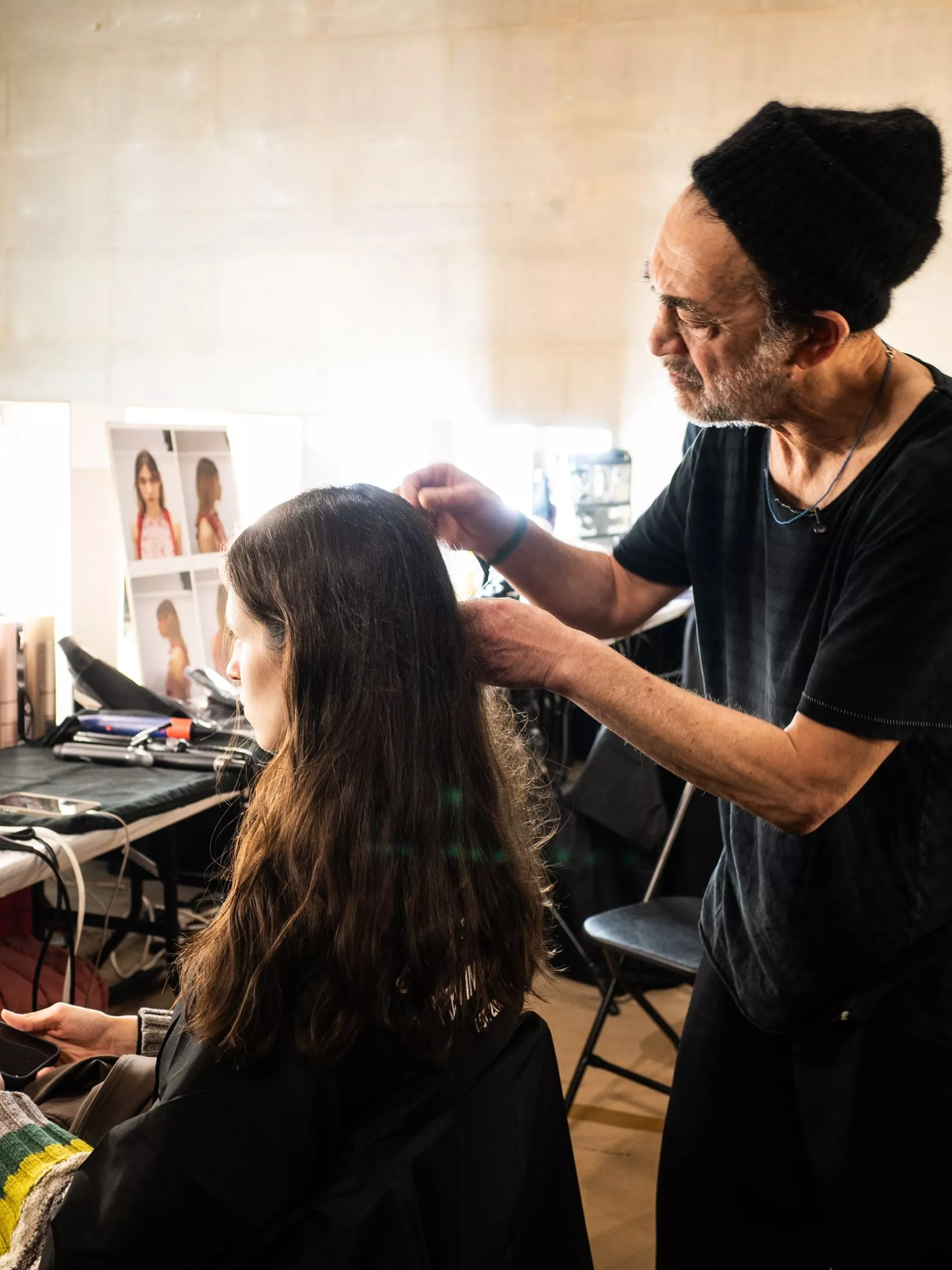 Celebrity hair stylist Eugene Souleiman preparing a model's hair backstage at Erdem