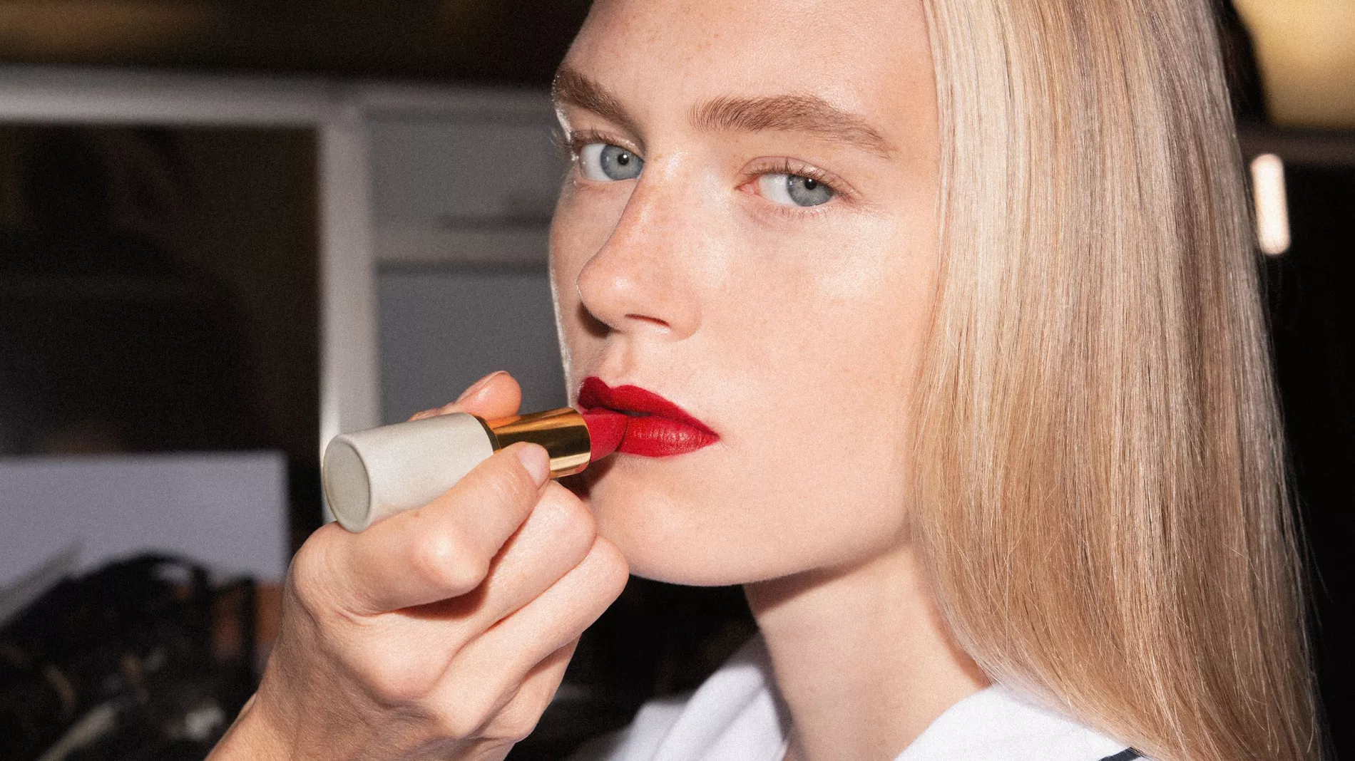 A model backstage at Victoria Beckham SS27 has red lipstick applied
