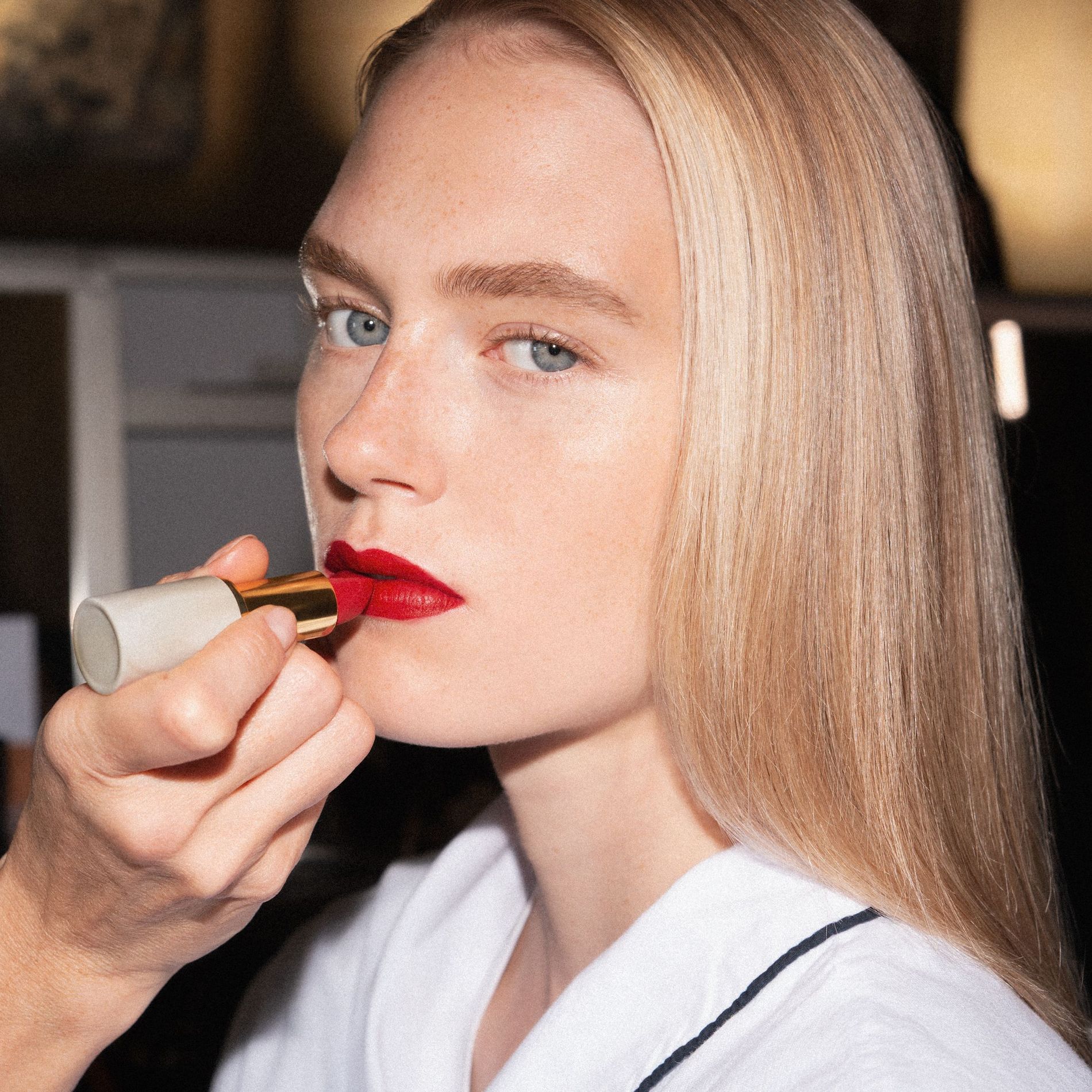 A model backstage at Victoria Beckham SS27 has red lipstick applied