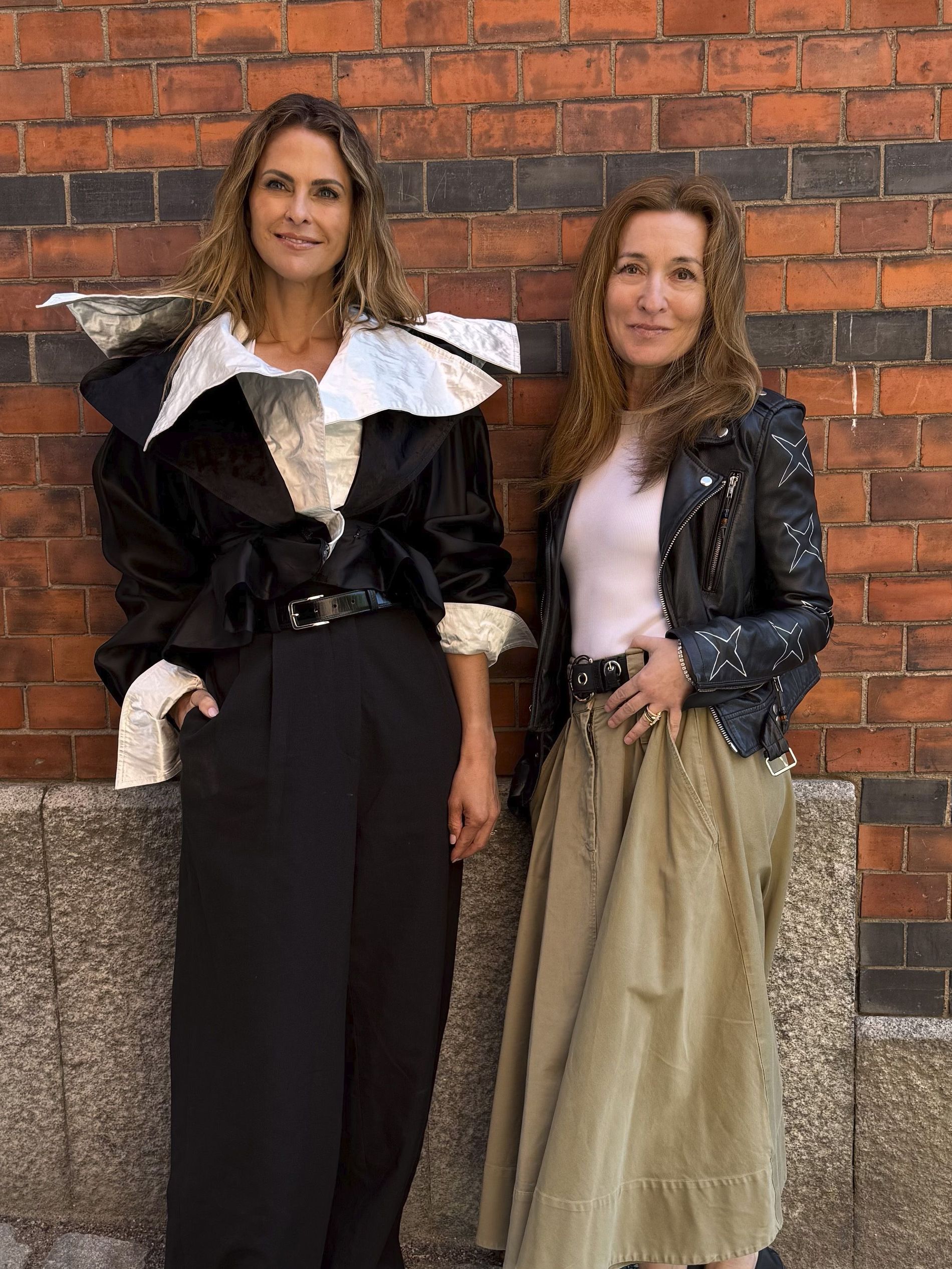 Princess Madeleine and Martina Bonnier stand side by side by a brick wall