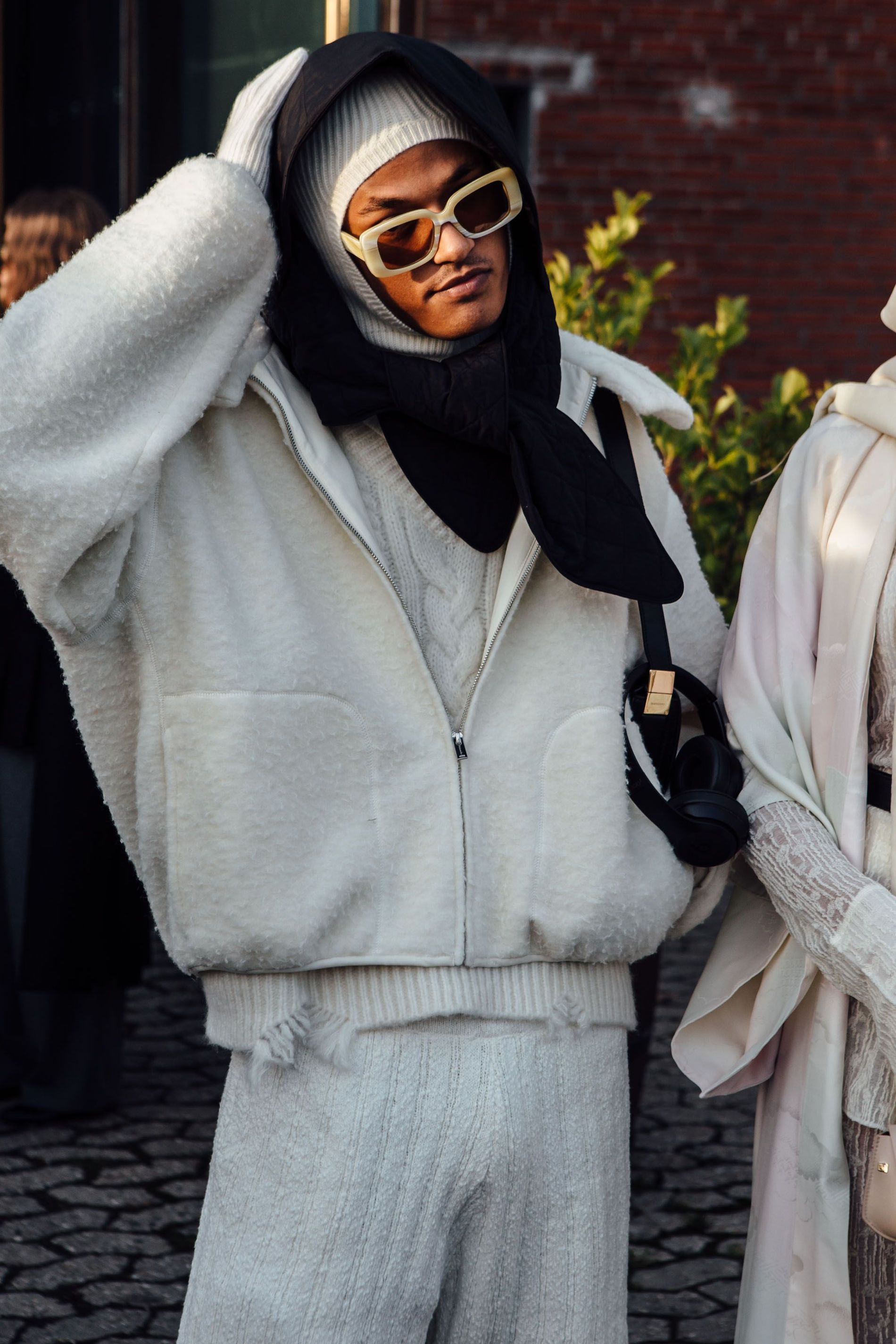 A guest wears a black padded head wrap, white balaclava, a white rib-knit set and a white teddy bomber jacket