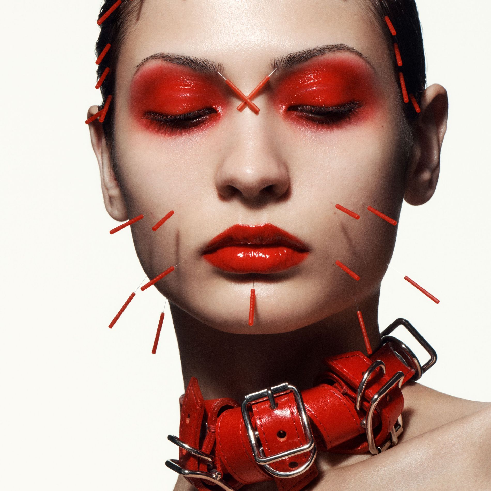 Model wearing red makeup and red acupuncture needles