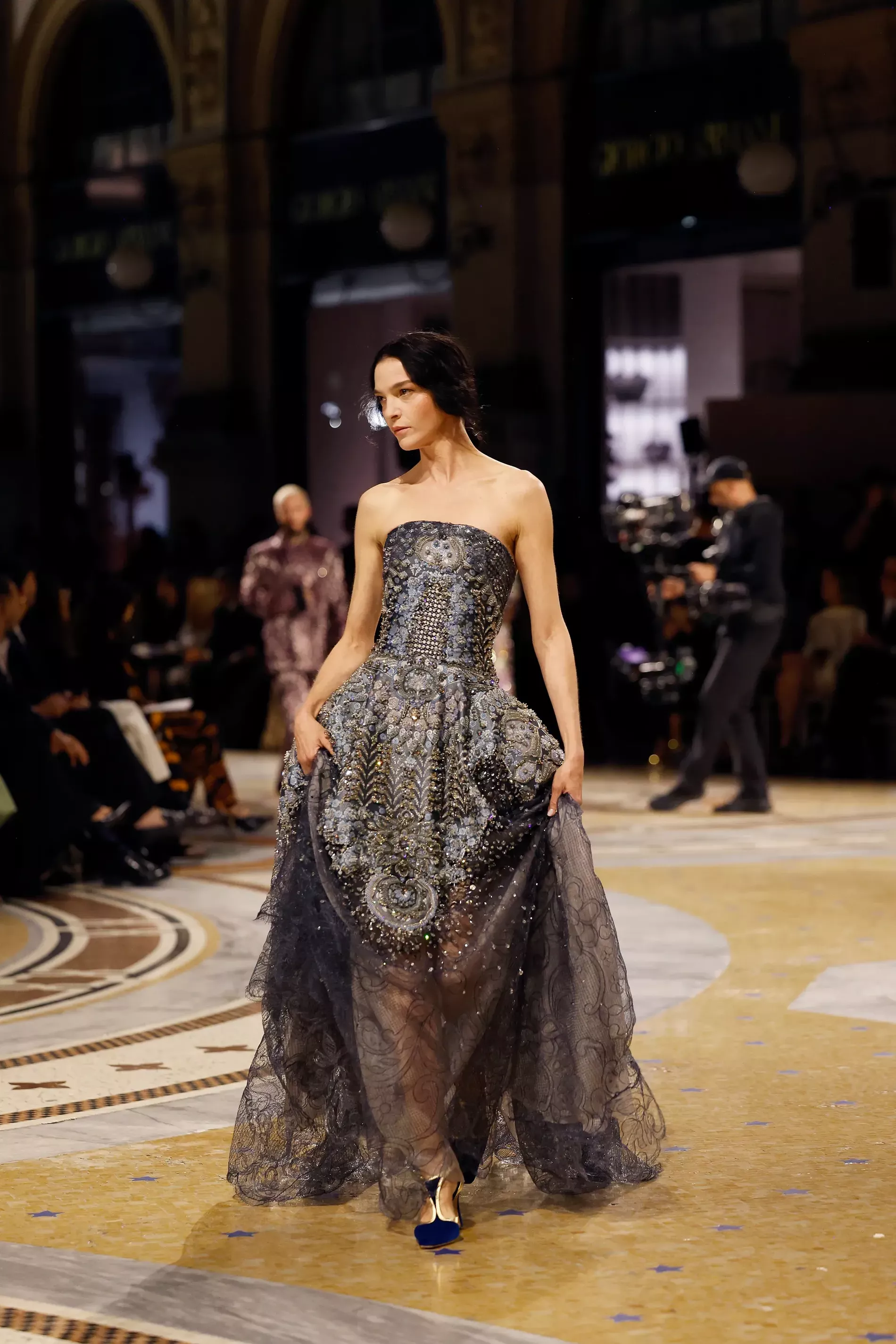 Mariacarla Boscono walking in Milan fashion week wearing a grey floor lenght dress