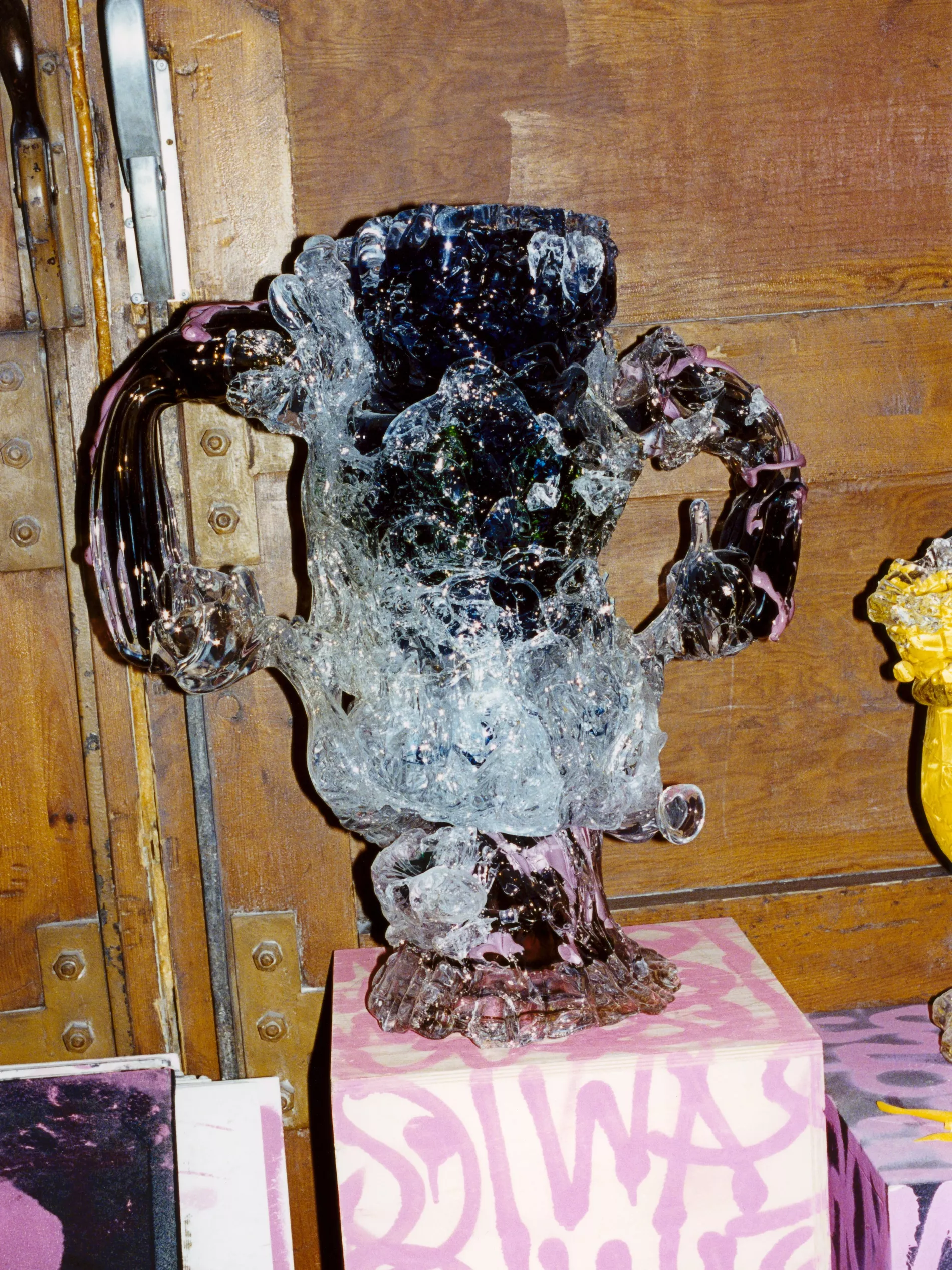 Highley detailed glass sculptured standing on a grafitti podiumwith a wooden background 