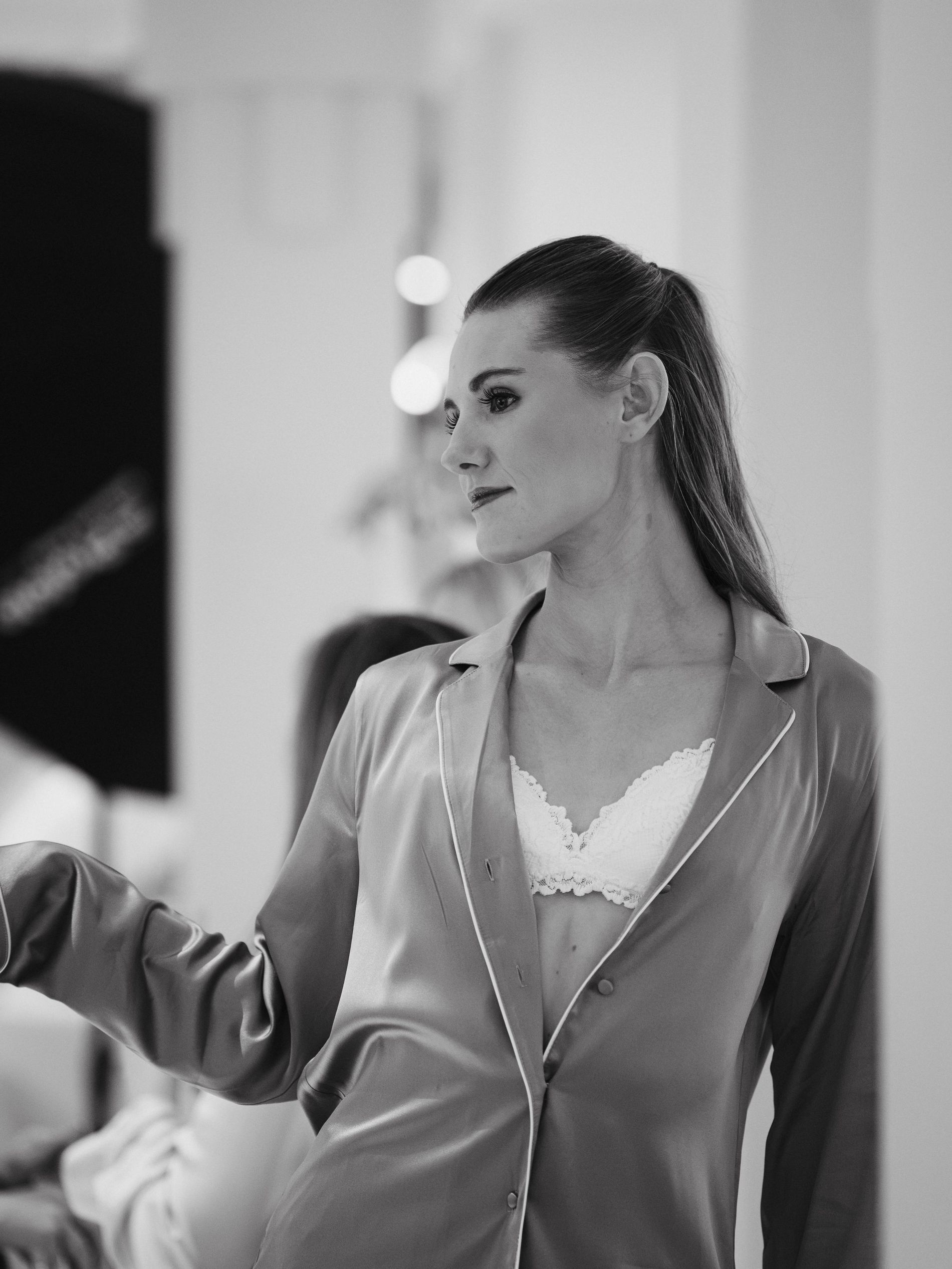A black and white photo of a women wearing a silk pyjamas and a white lace bra