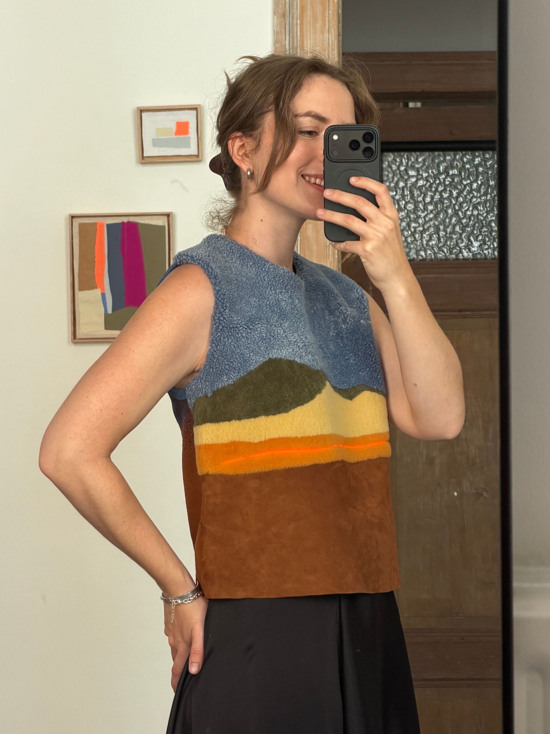 The writer wearing the sleeveless calf leather and bouclé wool top from the Caroline Hélain x Longchamp collection, its colour-blocked panels running from blue shearling to burnt orange suede.