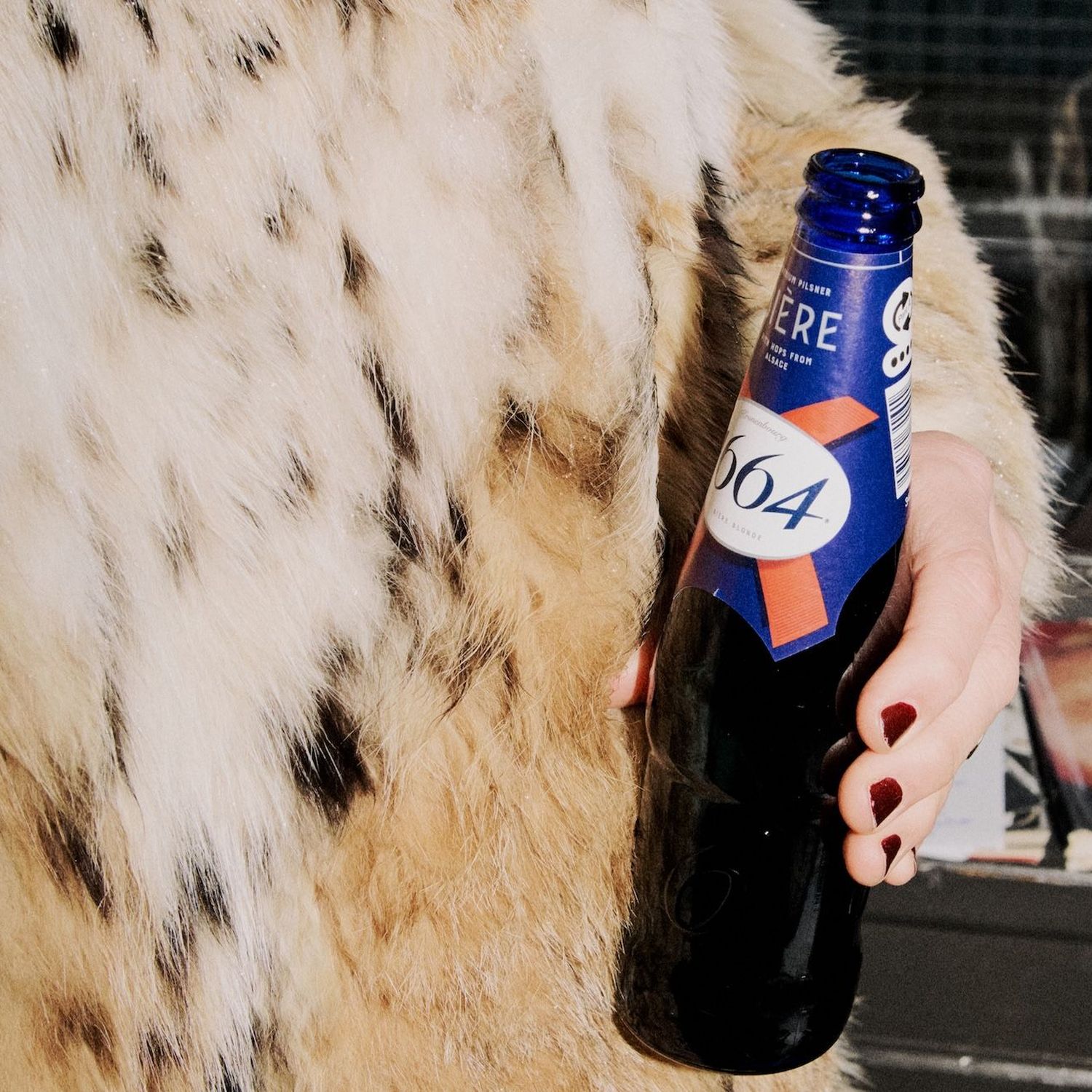 1664 bottle being held by a woman in faux-fur coat
