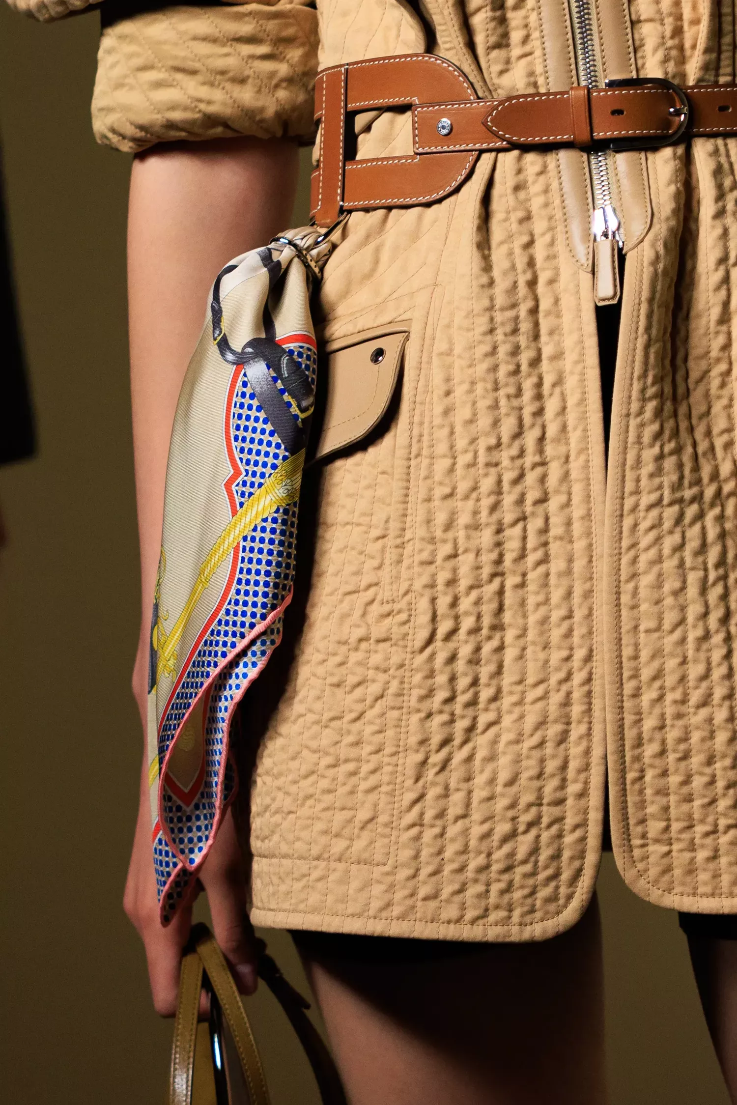 A close-up of a scarf ring detail at Hermès spring/summer 2026 ready-to-wear where a silk scarf is attached to a leather belt