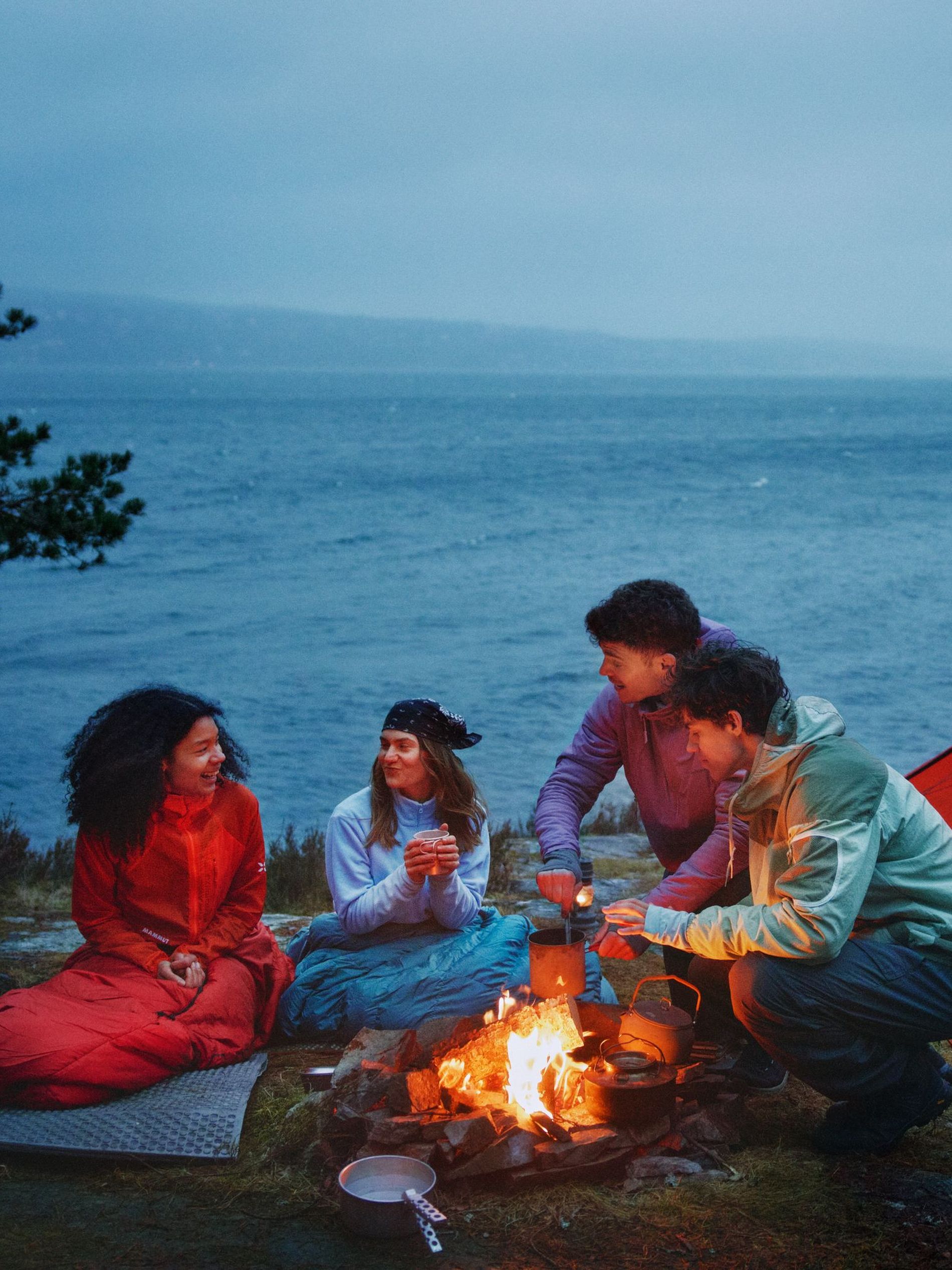 the stars of Zalando's outdoor campaign camping lakeside gathered around a bonfire