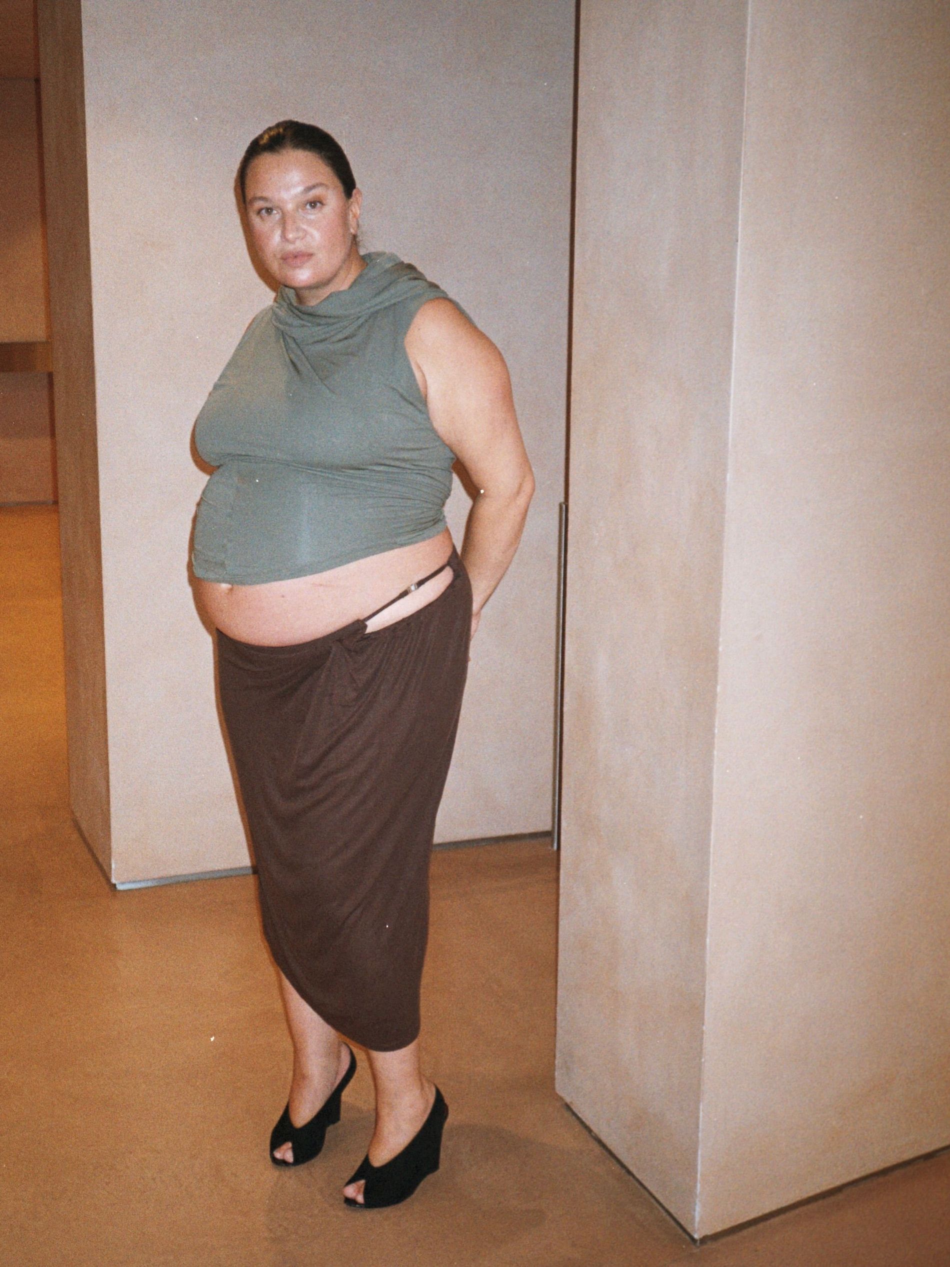 Nadia wears khaki high neck tank top and brown maxi skirt with hip cut out