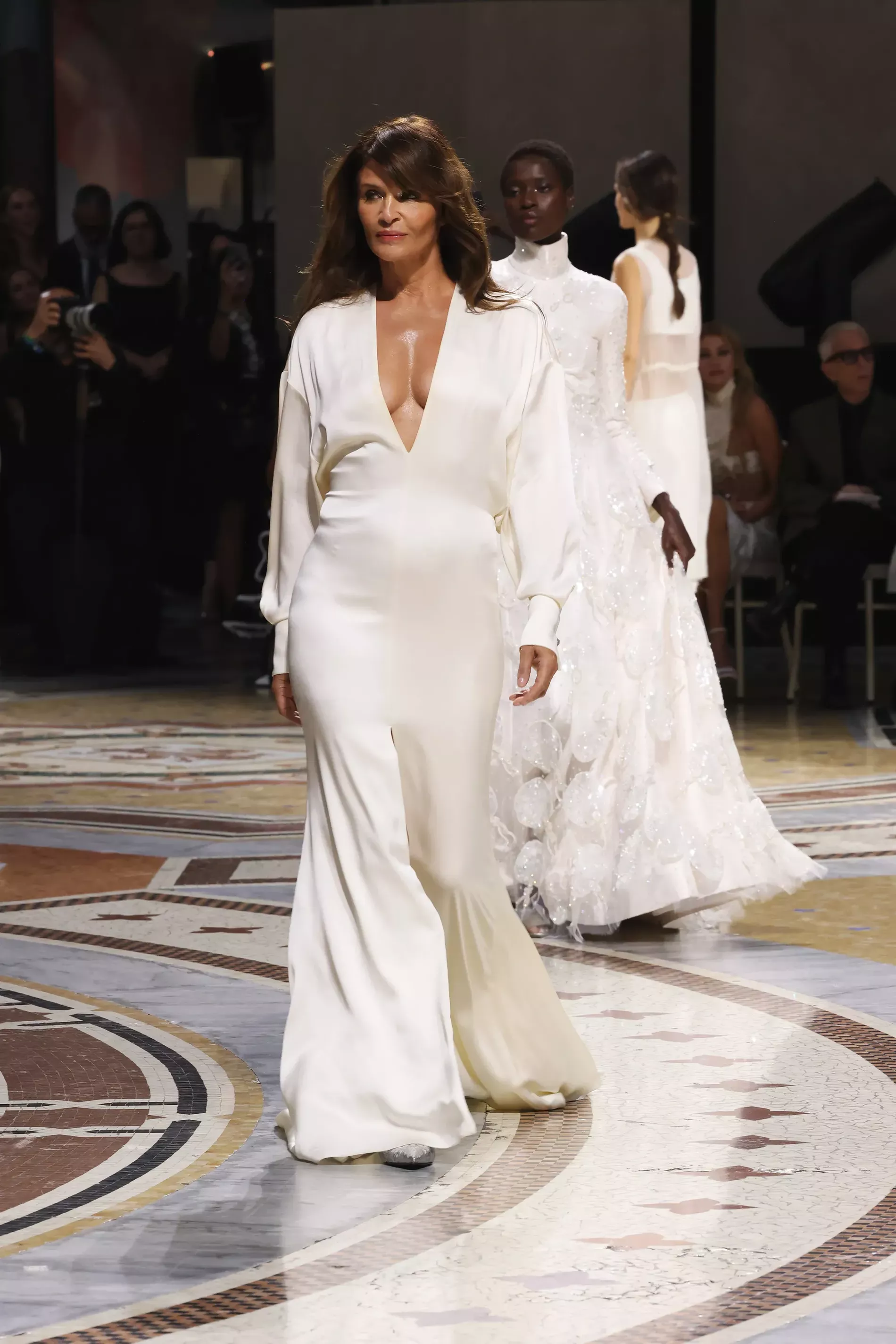 Helena Christensen Helena Christensen appears on the runway in an elegant, custom-made ivory silk gown featuring a deep V-neckline, Brunello Cucinelli custom creation, in Galleria Vittorio Emanuele II, Milan fashion week