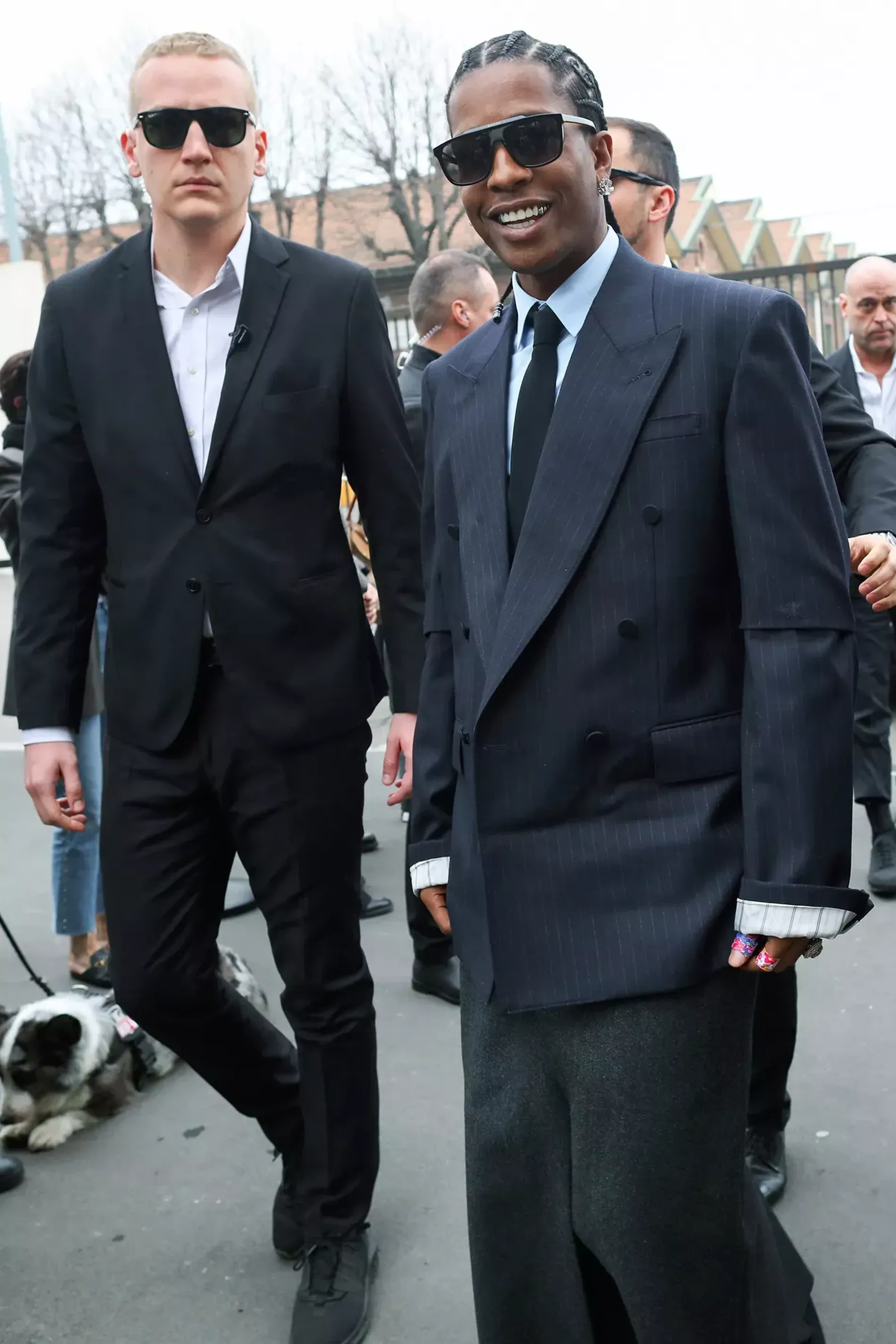 Milan Fashion Week guest wears dark blue pinstripe blazer with light blue shirt and black tie