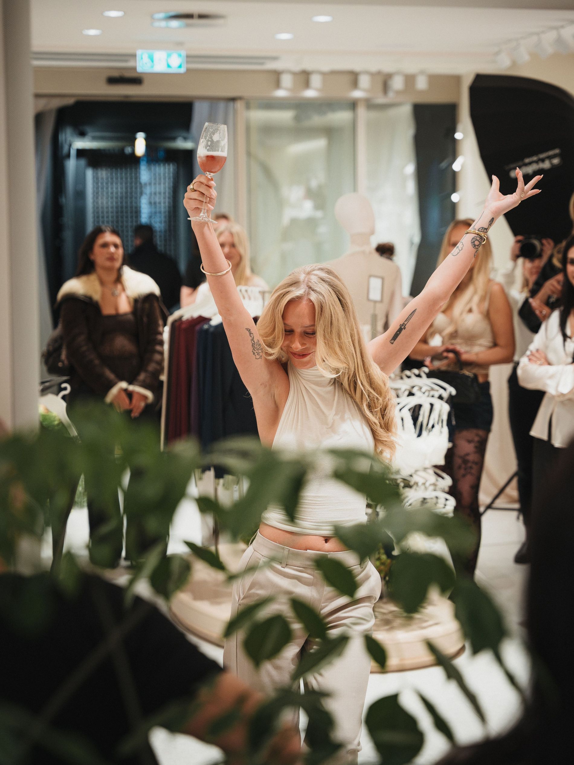 Blonde girl on the Intimissimi X Vogue Scandinavia opening event dancing with a glas of champagne