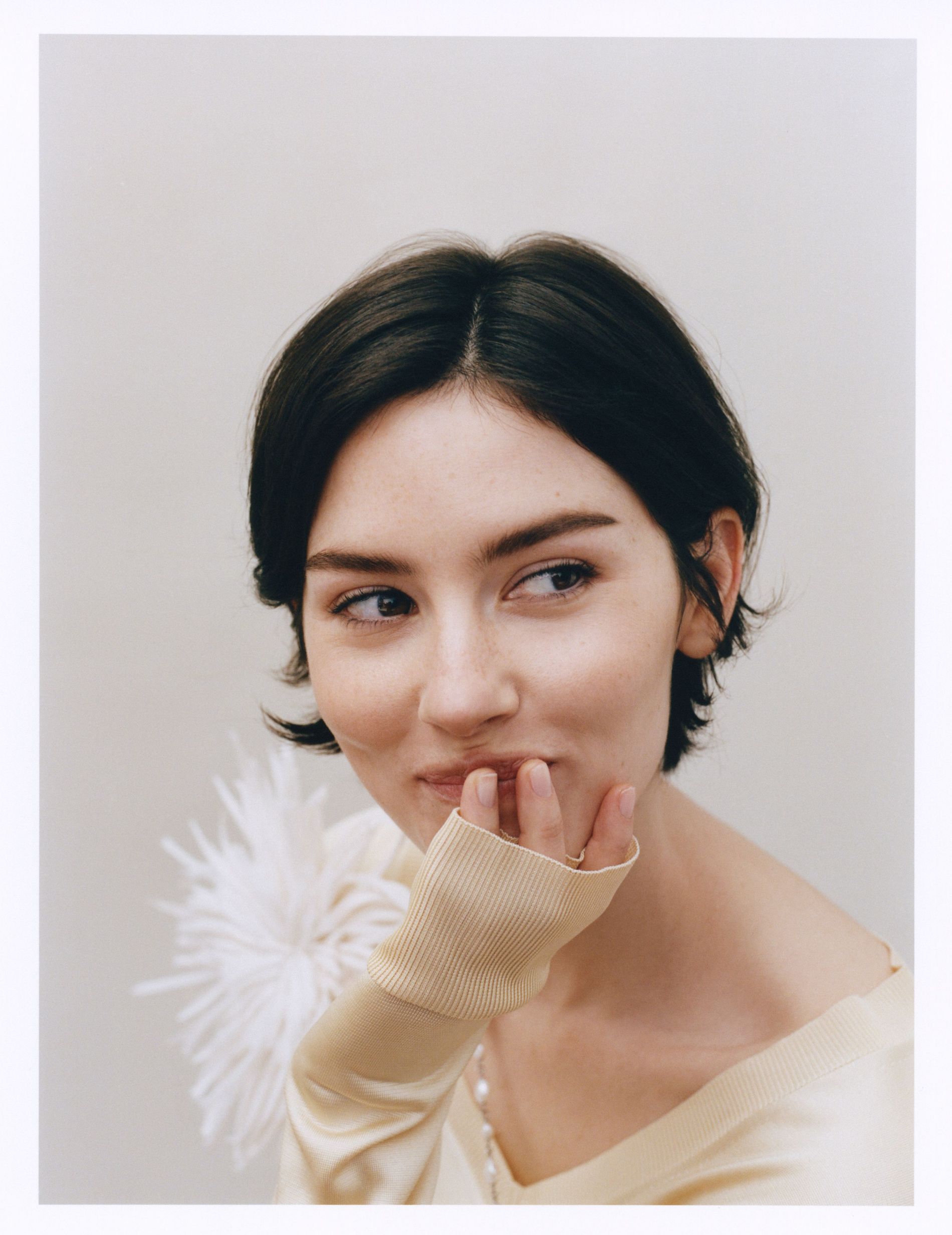Gracie Abrams poses for a headshot in a. pale silk sweater