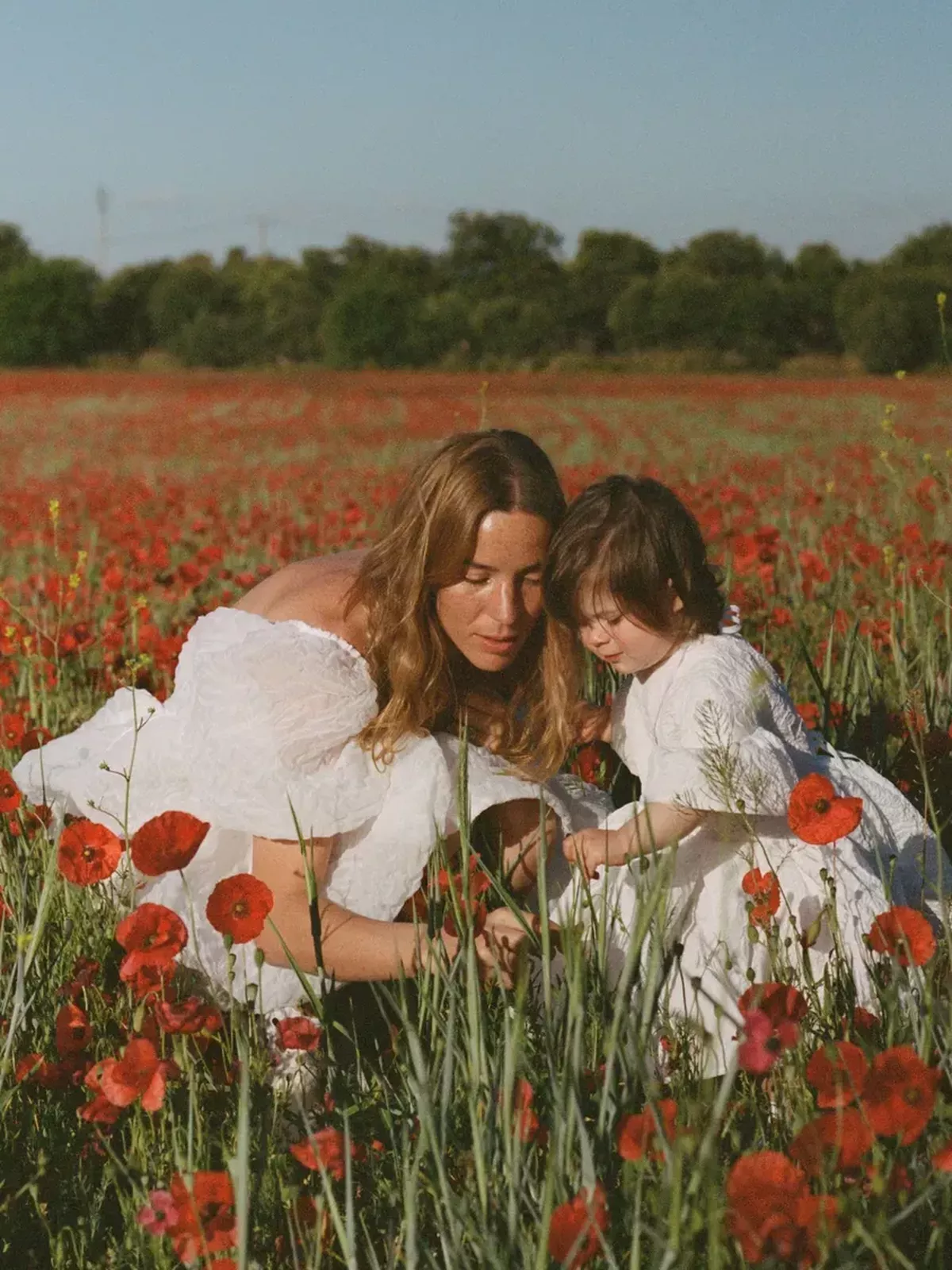 A mother and her child pose in a poppy field