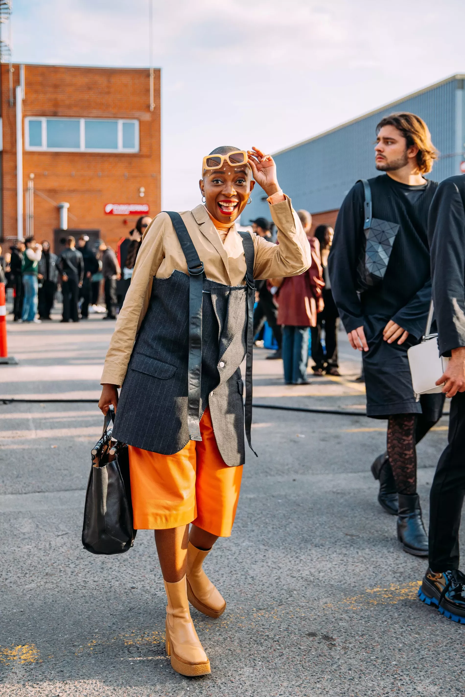 Copenhagen Fashion Week guest wears pinstripe vest over beige suit and orange shorts