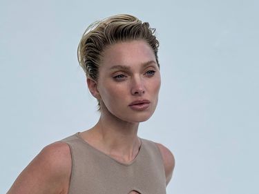 Elsa Hosk poses in a beige body con dress with short, slicked back hair 