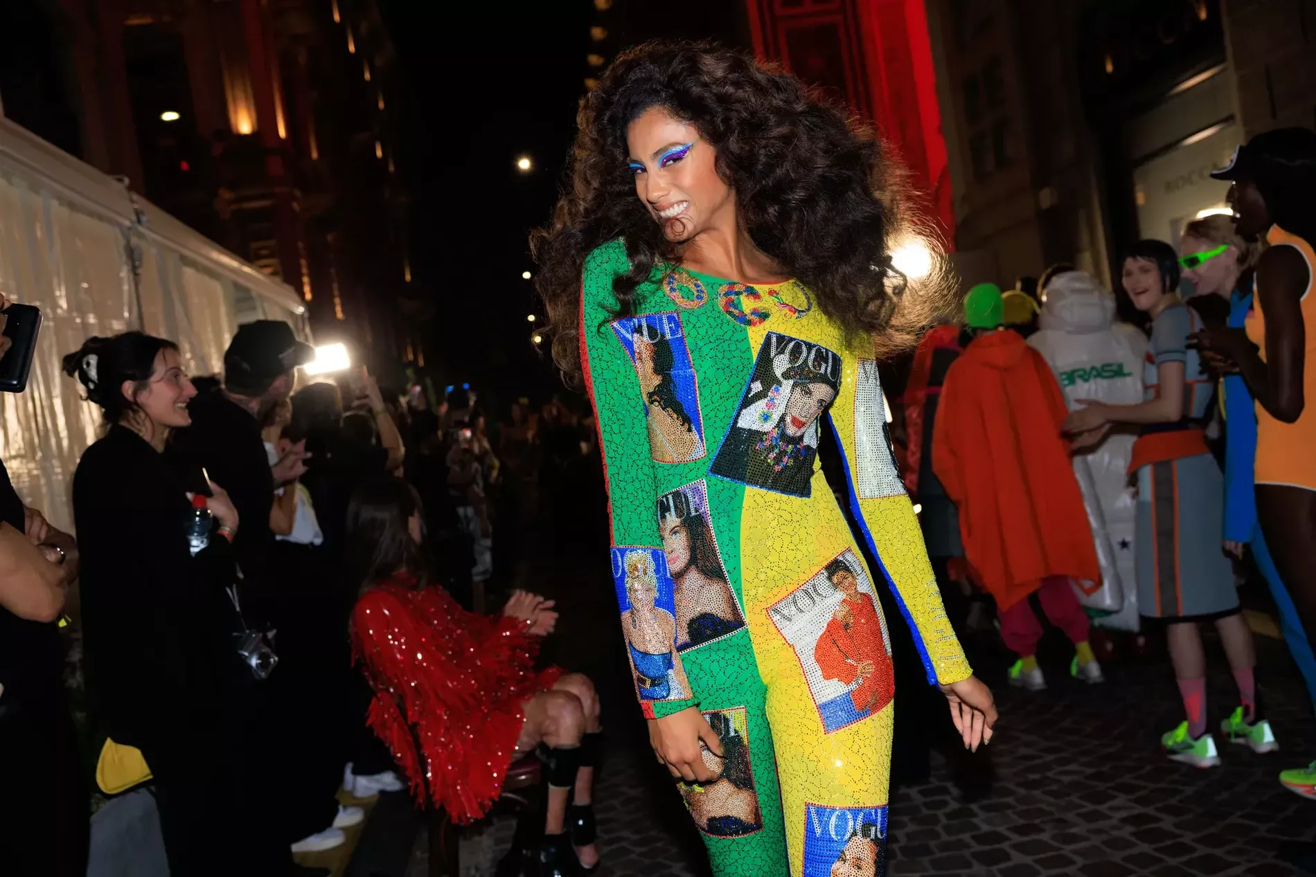 Imaan Hammam in Milan fashion week 2026 wearing The selected region features a model wearing an iconic, multi-colored, bead-embellished Versace Vogue-print catsuit, inspired by Gianni Versace's legendary Spring/Summer 1991 collection