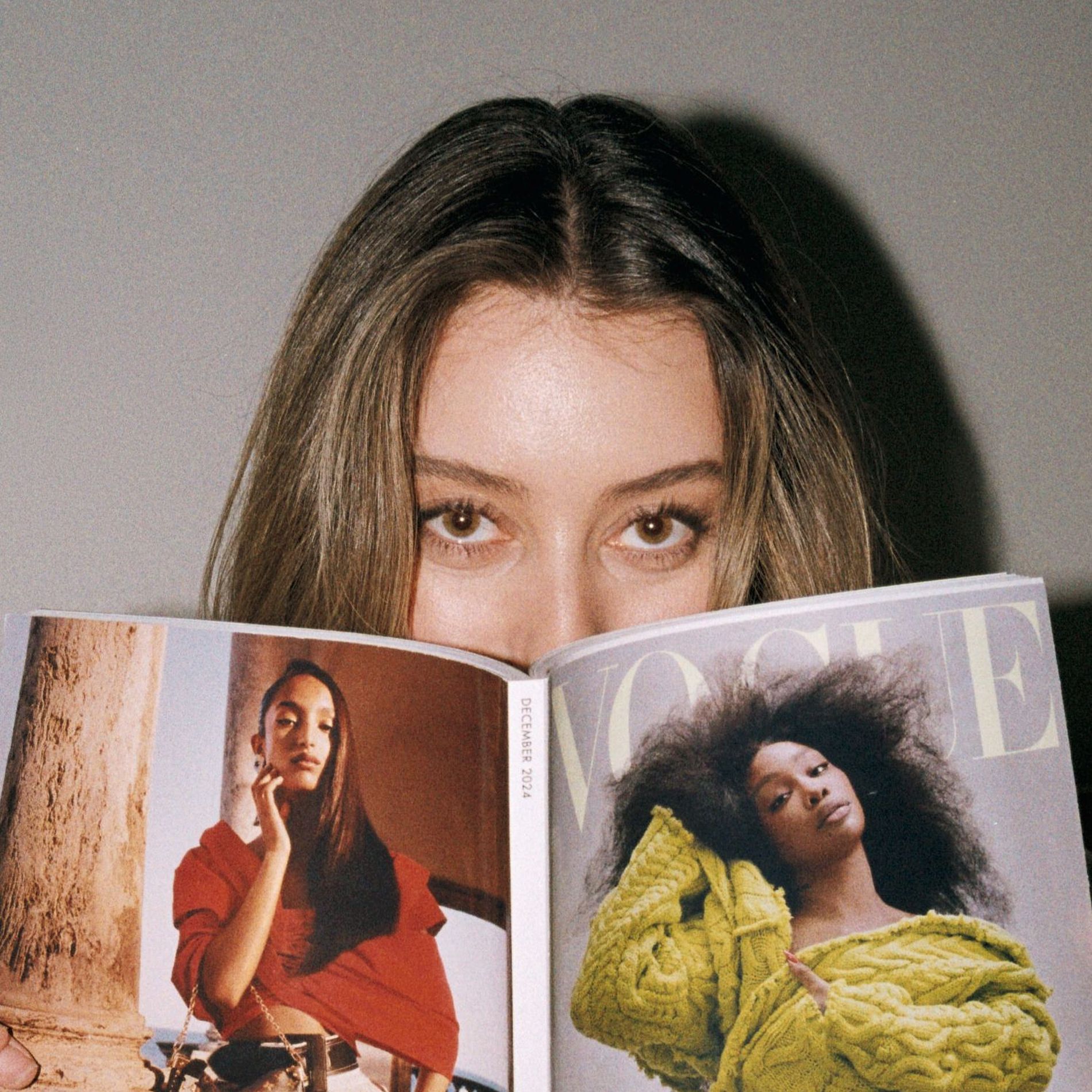 A model with brushed up brows is pictured reading a Vogue magazine
